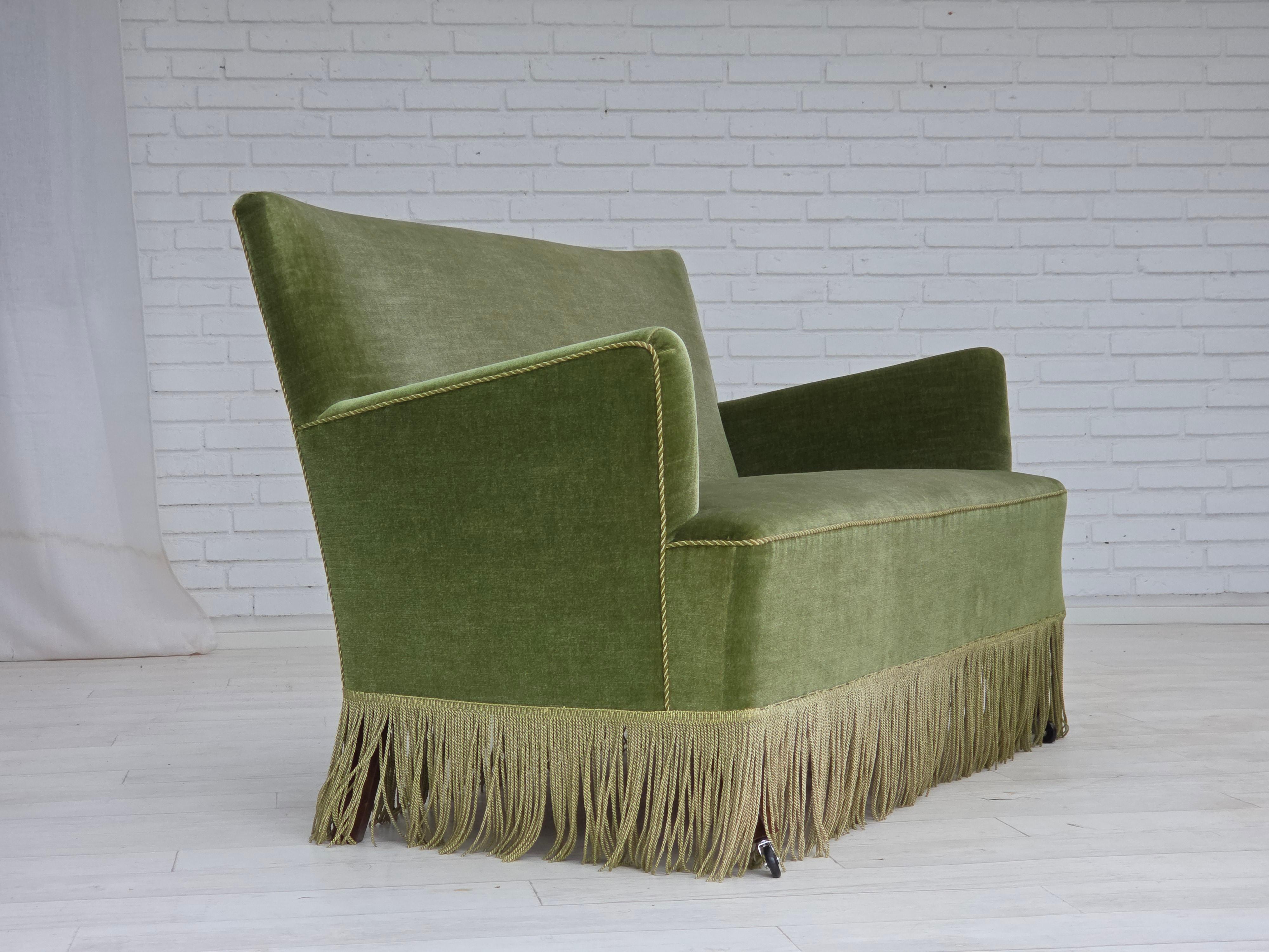 1970s, Danish 2-seater sofa. Original green furniture velour, beech wood legs, springs in the seat, wheels on the front legs. Extra covers for armrests. Original good condition: no smells, no stains and stable construction. Manufactured by Danish
