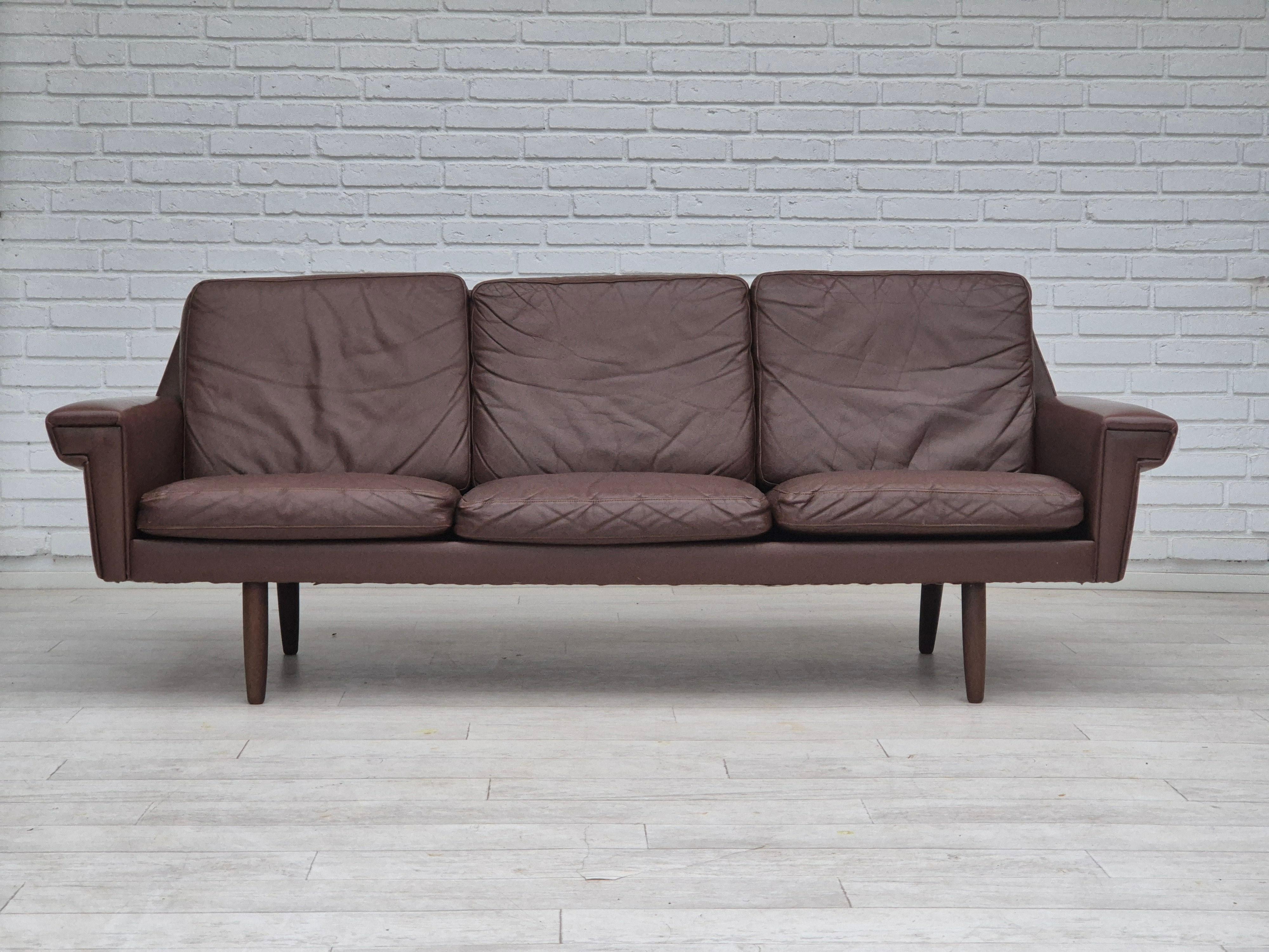 Sofá danés de 3 plazas de los años 70 en muy buen estado original: sin olores ni manchas. Diseño clásico danés de los años 70, una combinación de modernidad con estilo vintage danés. Cuero marrón original, patas de madera de haya. Fabricado por un