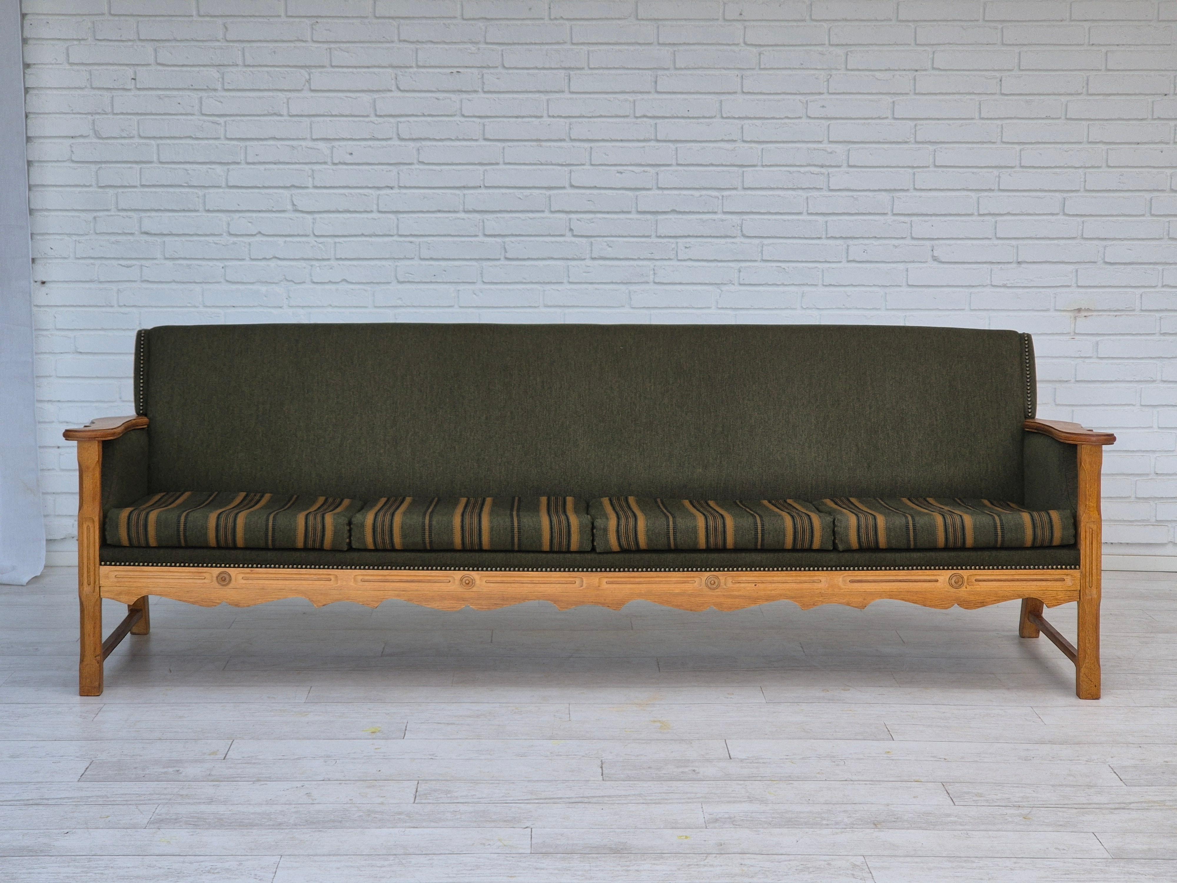 1970s, Danish 4 seater sofa in original very good condition: no smells and no stains. Furniture green wool fabric, new furniture foam in seat cushions. Oak wood. Manufactured by Danish furniture manufacturer in about 1970-75s.