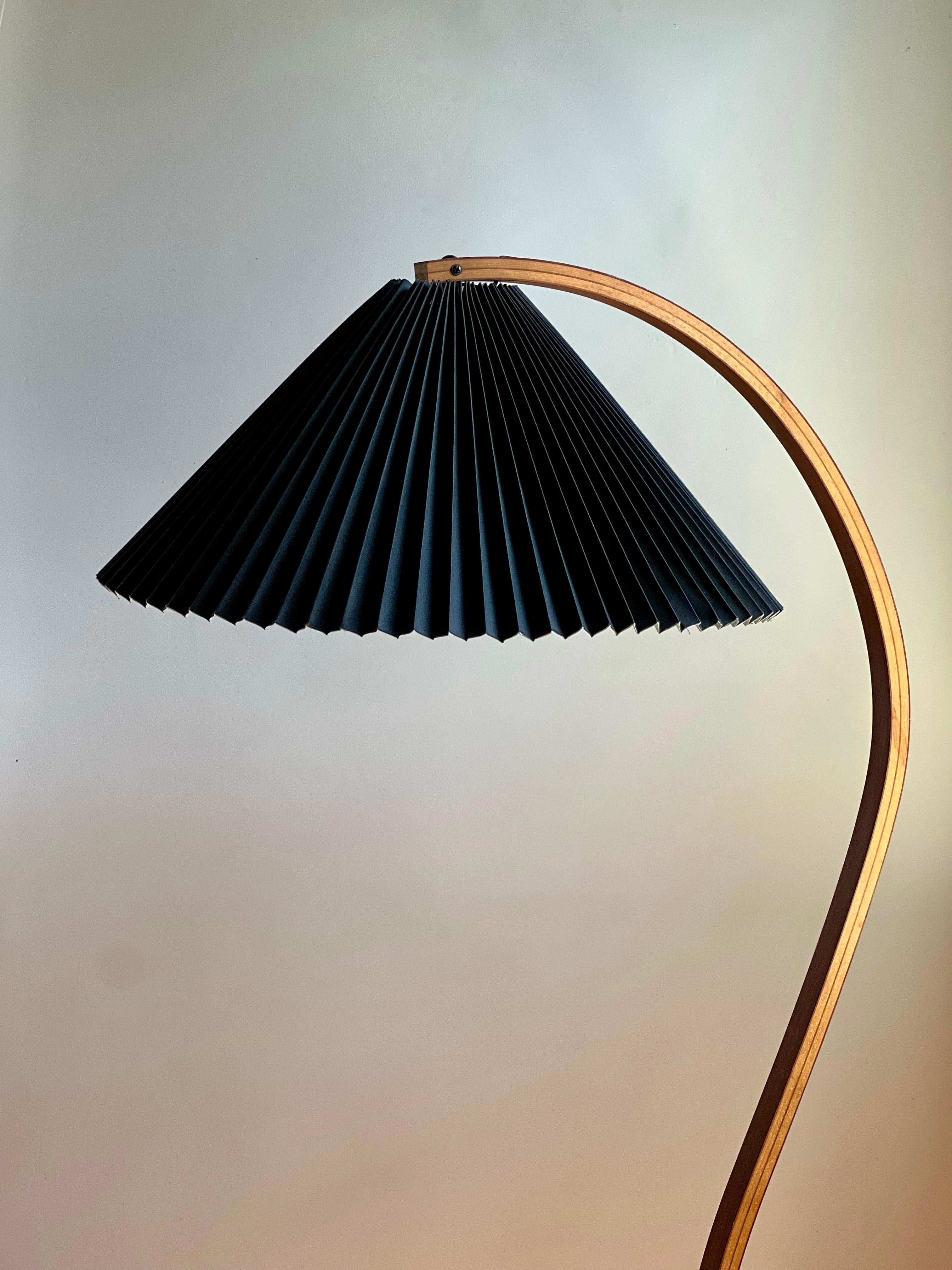 Questa lampada da terra vintage in teak Caprani, realizzata in Danimarca negli anni '70, è un'icona del design moderno di metà secolo. Con un fusto curvo in legno curvato, una base a mezzaluna in ghisa e un originale paralume in lino nero
