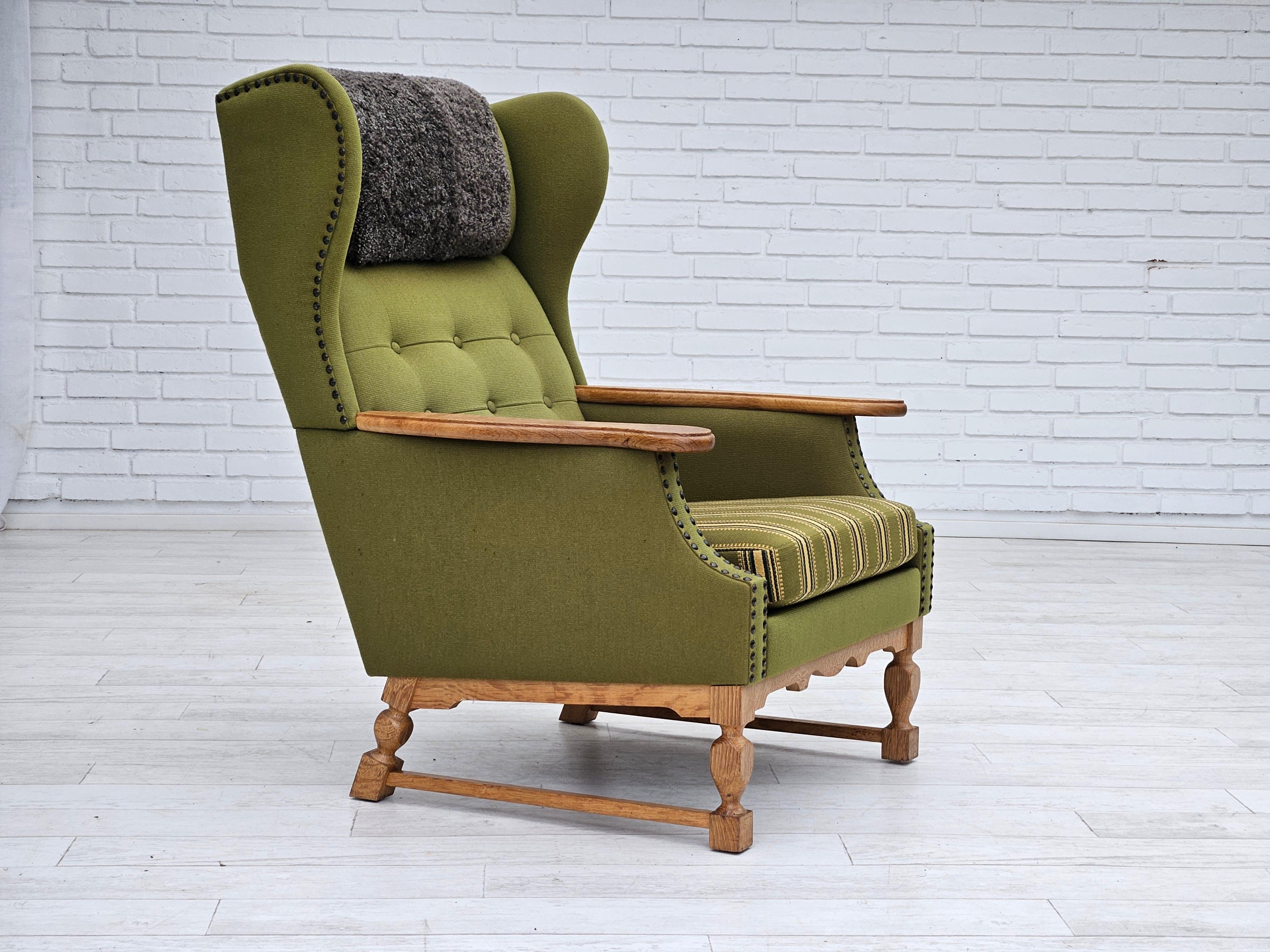 1970s, Danish highback armchair. Original very good condition: no smells and no stains. Olive green furniture wool, genuine sheepskin neck pillow. Oak wood, springs in the seat cushion. Manufactured by Danish furniture manufacturer in about 1970s.