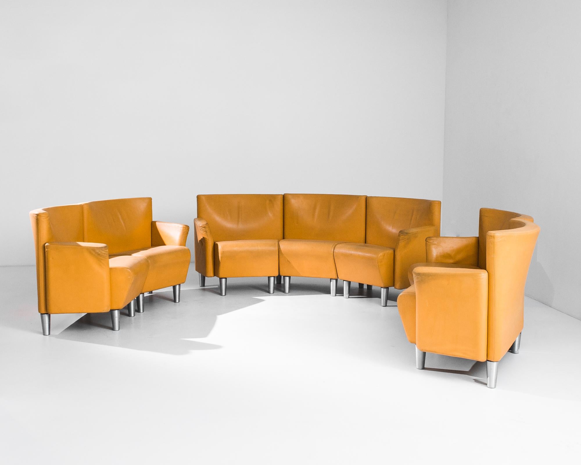 A 1970s three piece sofa set by Danish furniture manufacturer Eric Jorgensen, composed of a three-seater sofa, a love-seat and an armchair. Mustard-orange leather gives a rich pop of color, while conical silver metal feet give a retro-futuristic