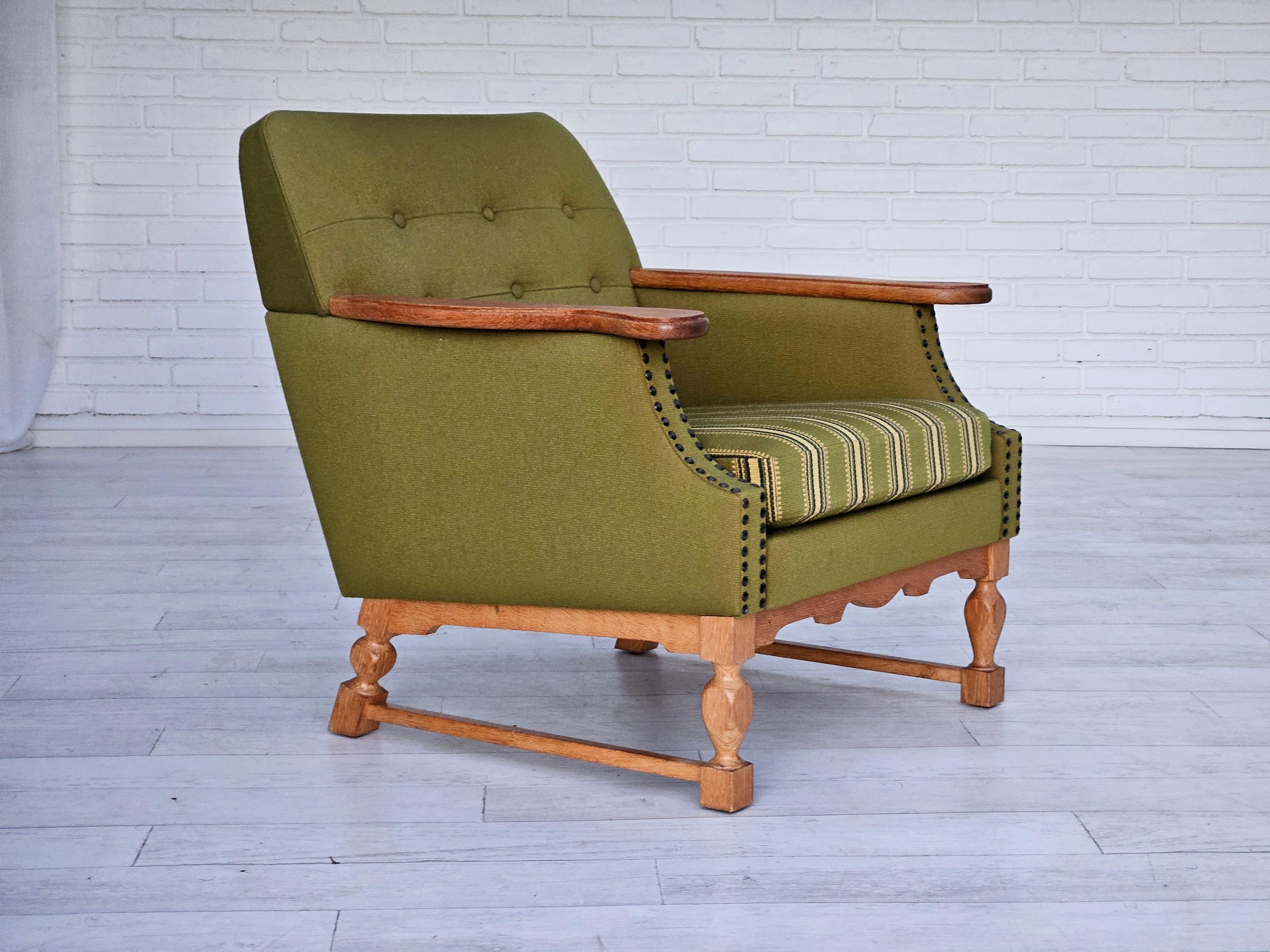 1970s, Danish lounge chair. Original very good condition: no smells and no stains. Original olive green furniture wool. Oak wood legs and armrest. Springs in the seat and back. Manufactured by Danish furniture manufacturer in about 1970s.