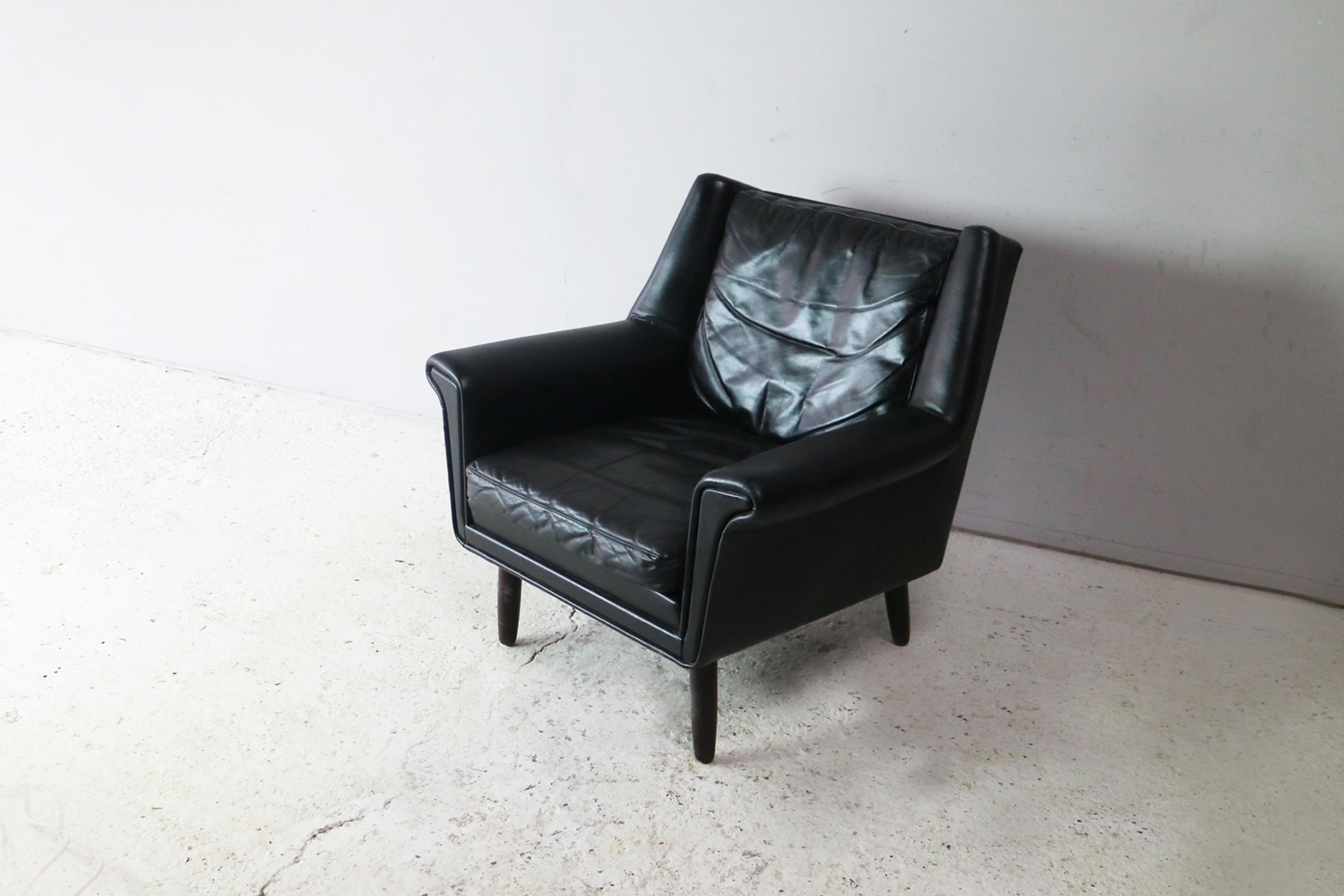 A low backed Danish armchair with a lovely shape. Upholstered in the original black leather, with turned teak legs

  