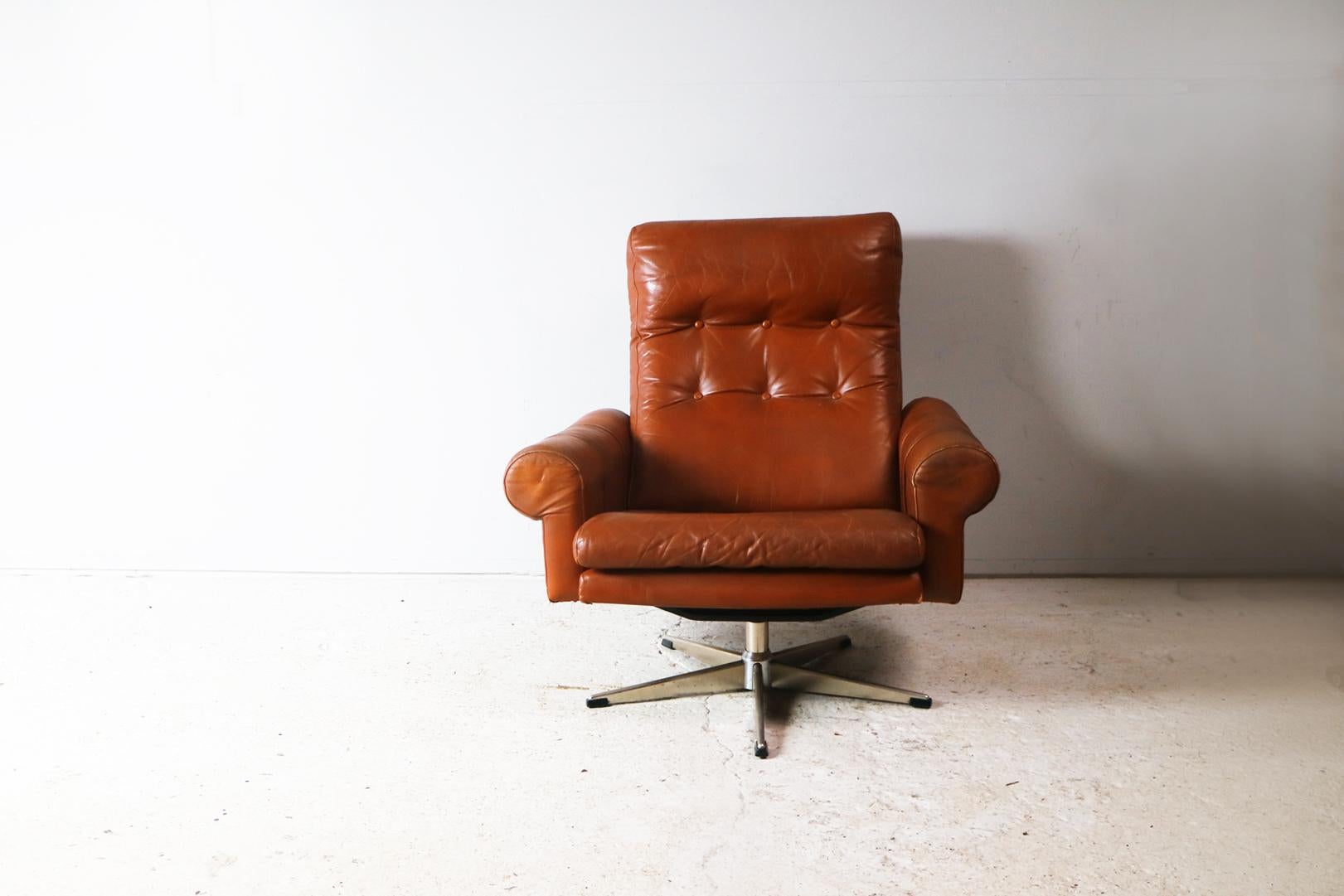 A stylish and extremely comfortable Danish Mid-Century Modern armchair. Upholstered in the original dark tan upholstery which is in very good condition. Distinctive rounded arms with strap details. Button detailing to the backrest and seat.