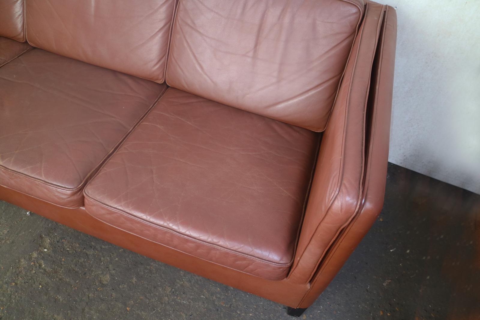 A handsome and stylish high sided Danish 1970s sofa, with the original chocolate brown leather upholstery. Sits on dark stained square beech legs.