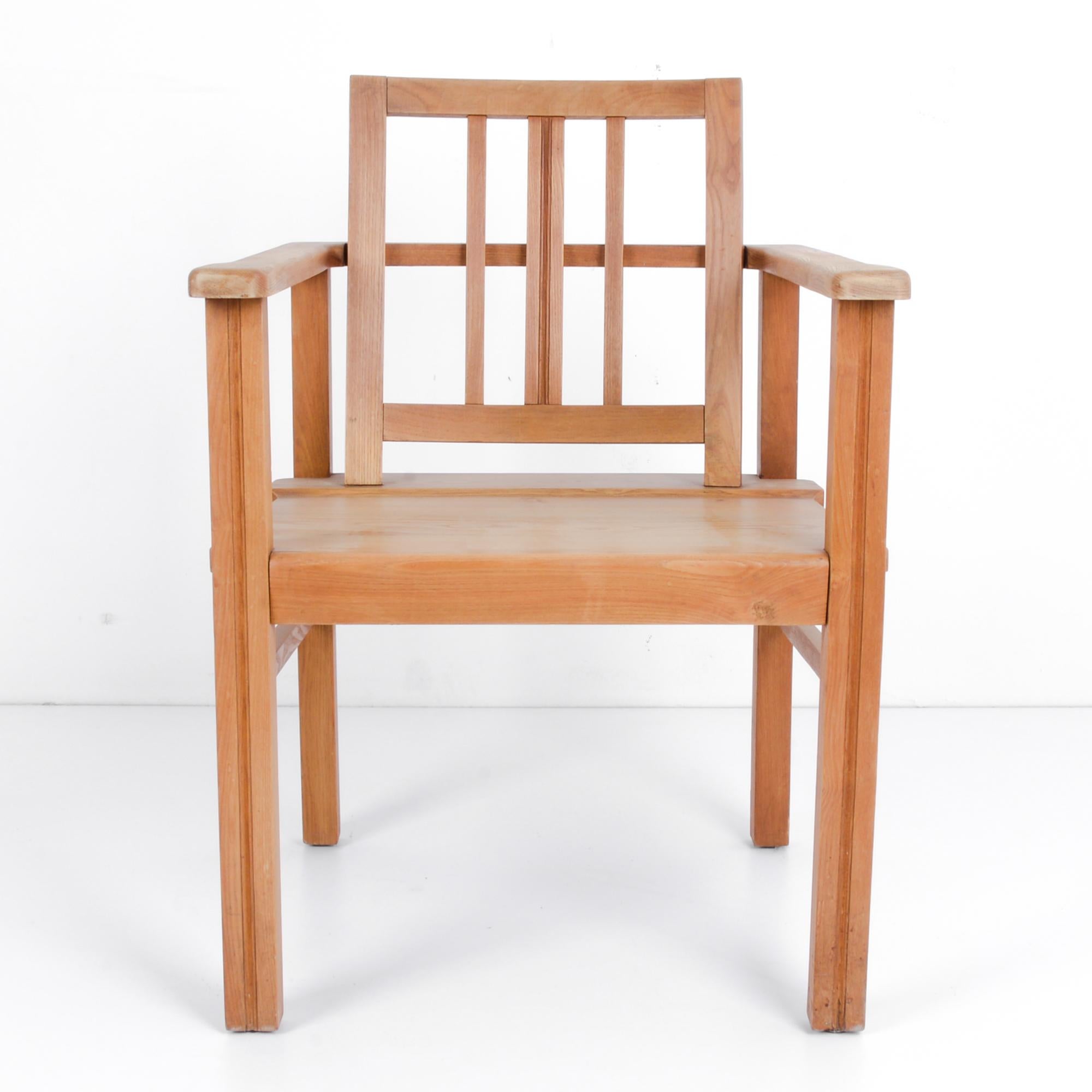 This wooden armchair was made in Denmark, circa 1970, and features a geometric silhouette. The slats of the backrest and spaces between the armrests and seats give the chair an airiness, which plays with the wide proportions and angularity of the