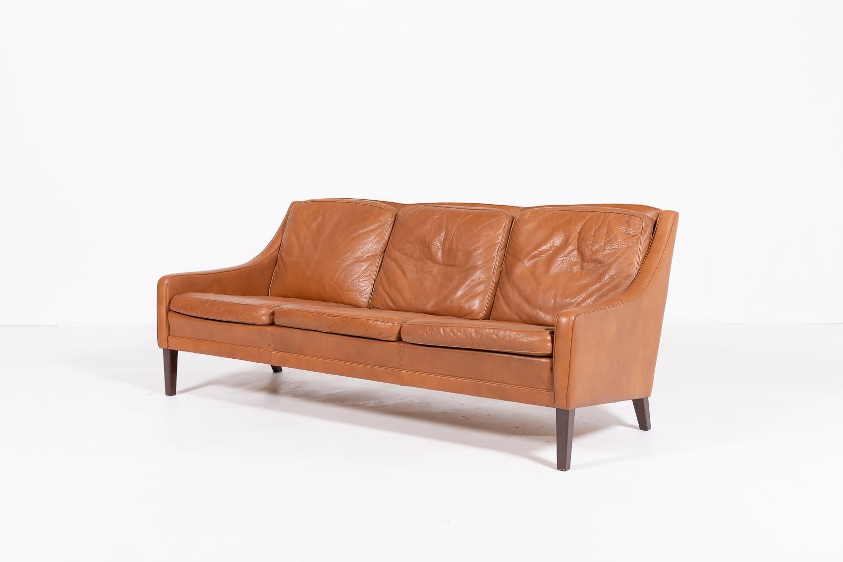 Danish Modern three-seat cognac leather sofa on varnished wood legs, loose cushions.

Condition
Good, age related wear and patina.

Dimensions
width: 180 cm
depth: 82 cm
height: 78 cm
seat height: 41 cm