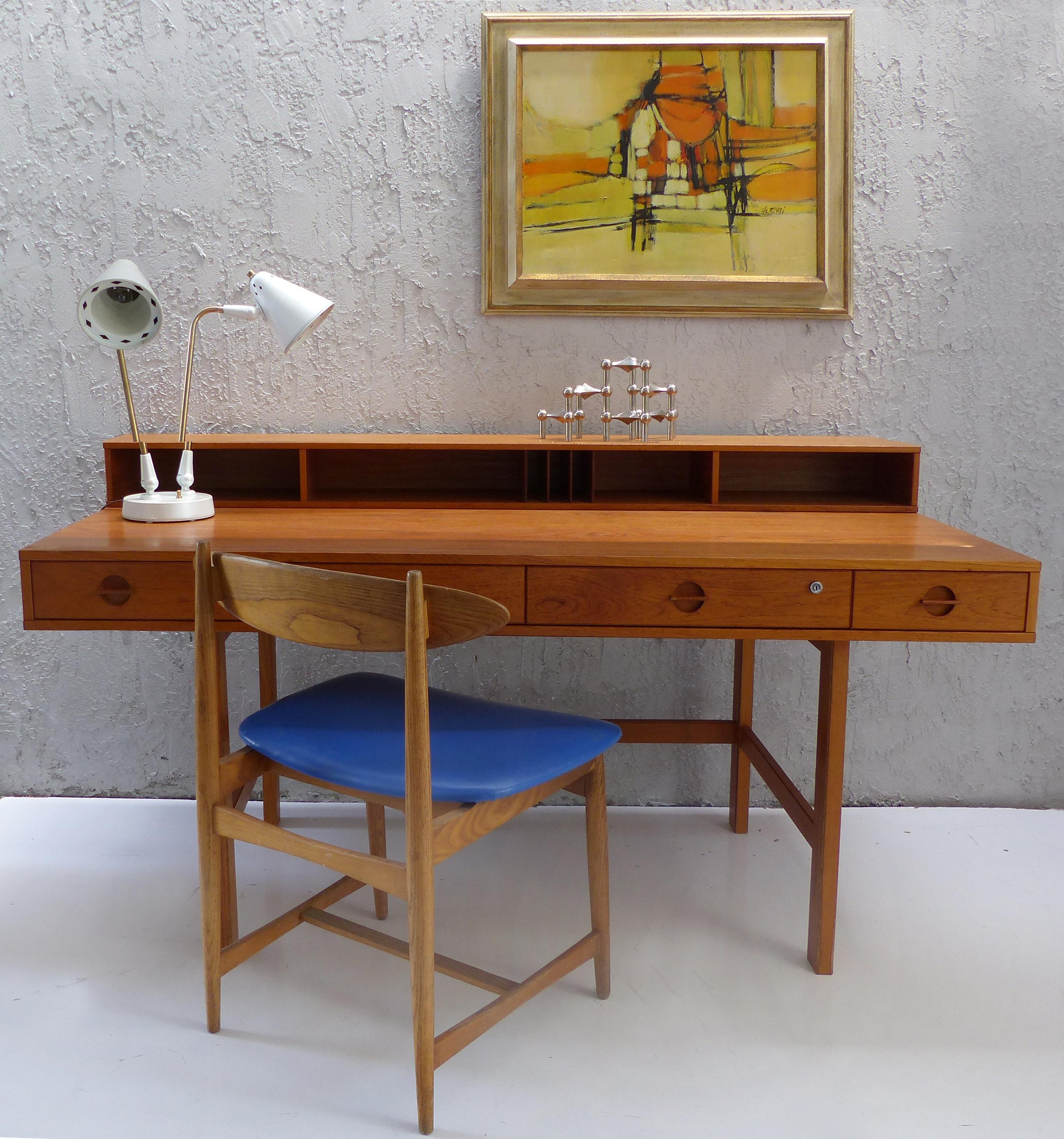 Offered for sale is a 1970s Danish modern writing desk by Peter Løvig Nielsen and Jens Quistgaard made of solid teak wood and teak veneer with a beautiful wood grain. The flip topend acts as cubby-hole storage that turns down to extend the surface