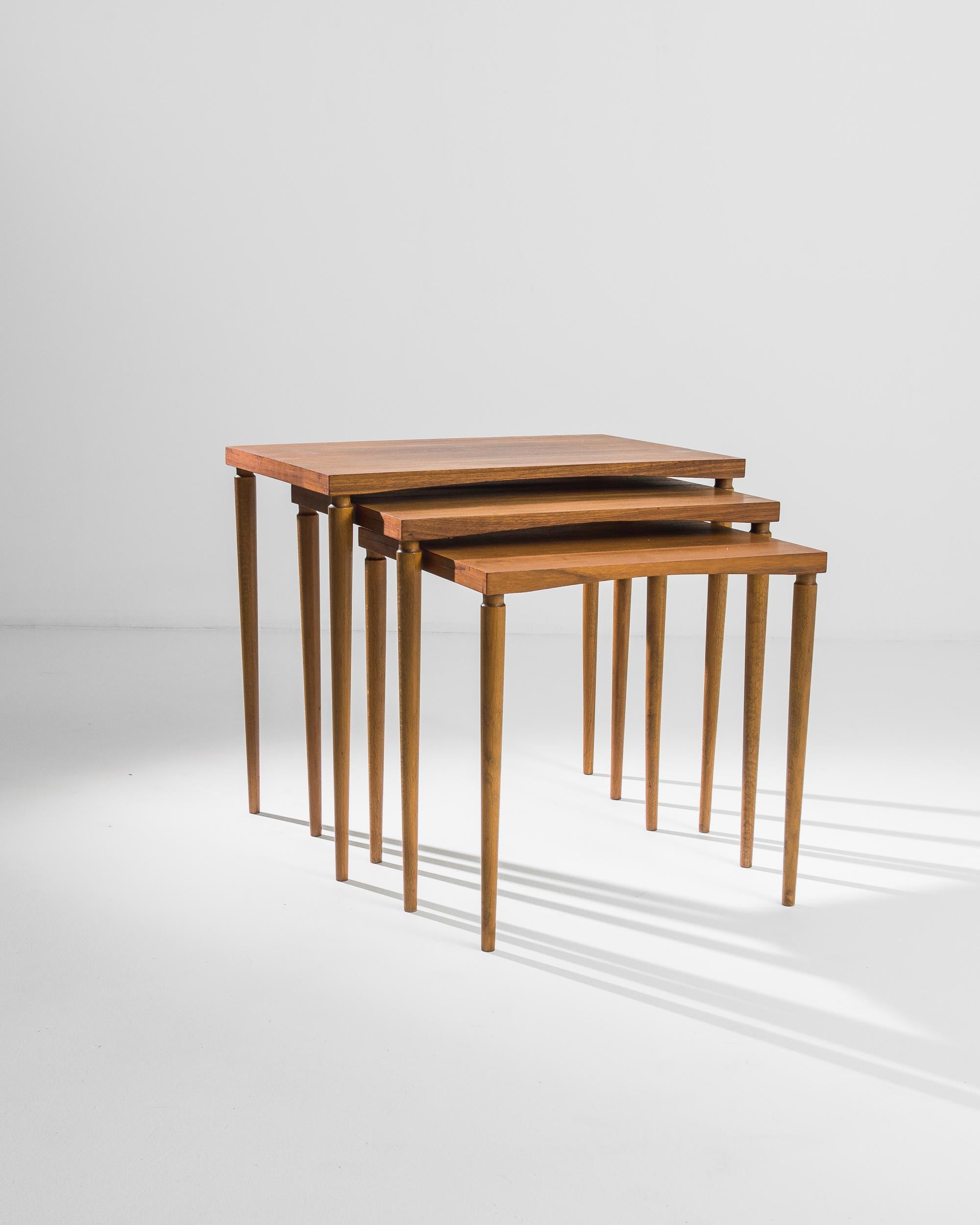 A set of mid-century nesting tables created in Denmark. Thin pencil legs and subtly sloping tops combine to form a subtle and elegant form. This set of tables is crafted using teak wood, indigenous to Indonesia, but considered a carpentry staple in
