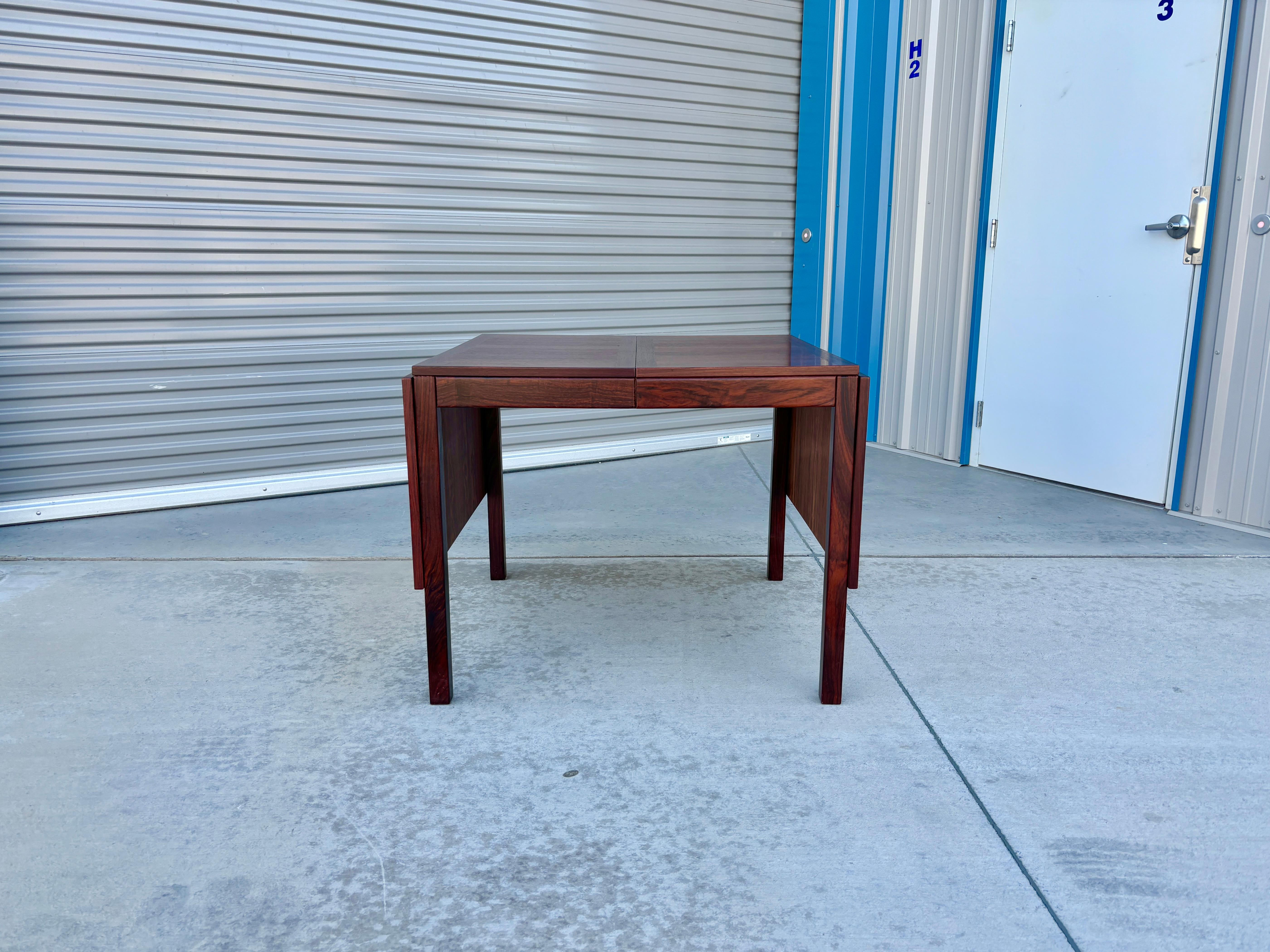 Danish Modern extended rosewood dining table was designed and manufactured by Vejle Stole & Møbelfabrik in Denmark in the 1970s. This beautiful dining table features a rosewood frame. The table has four extensions, two of which can be inserted into
