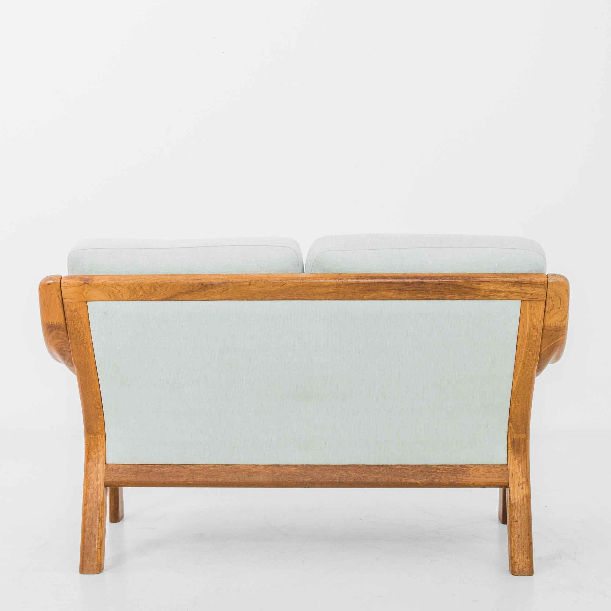 This two-seat teak sofa was manufactured in Denmark, circa 1970. In this elegantly composed design, soft cushions rests on a dynamic bent hardwood frame. A contrast of textures and colors, curves and straight lines, casual seating in typical