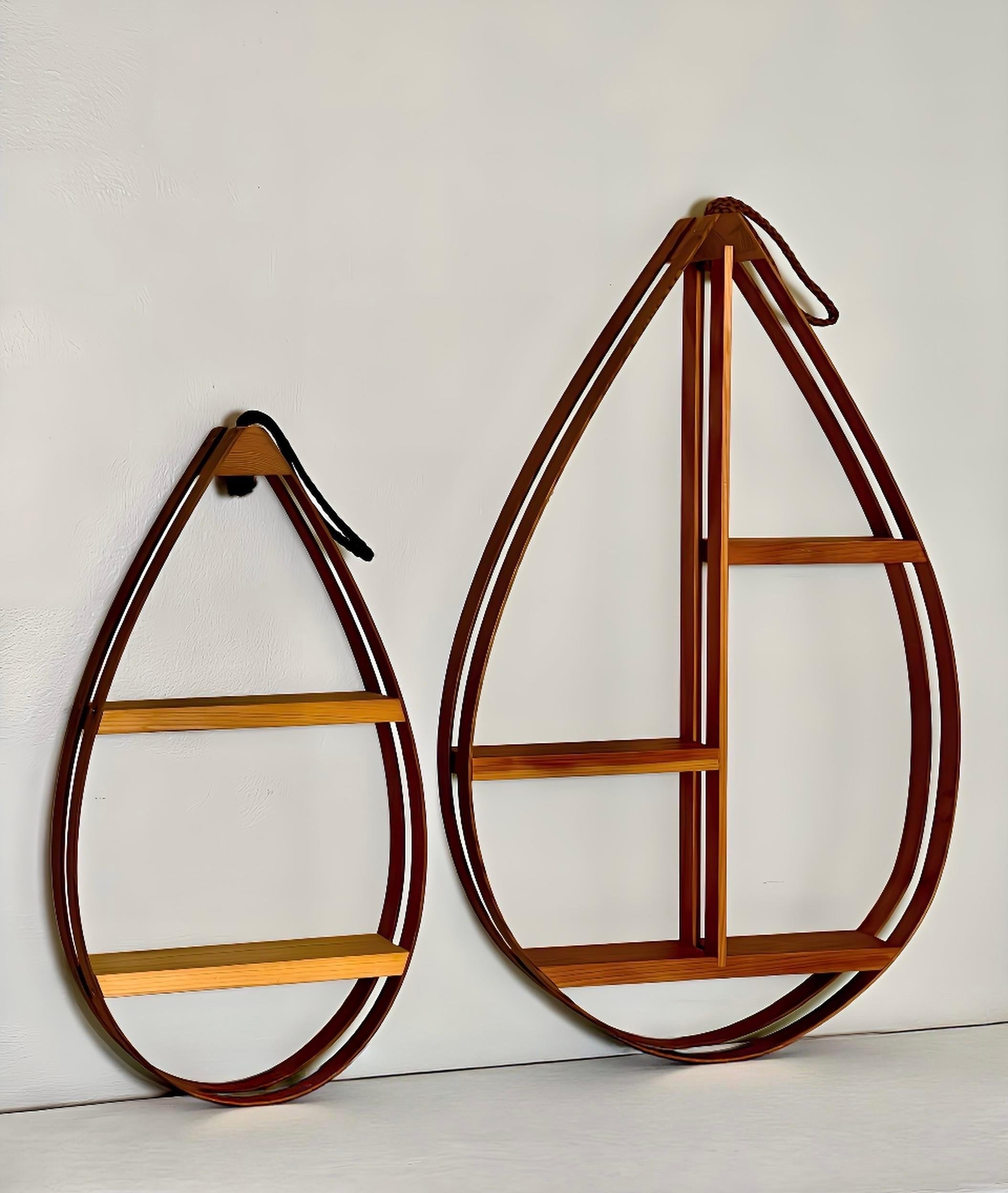 Vintage 1970s Danish modern teardrop bentwood hanging curio shelves. A coordinating pair in two sizes with a double bentwood frame topped with a rope hoop hanger and secured with copper nails. The organic modern teardrop shape has clean lines and an