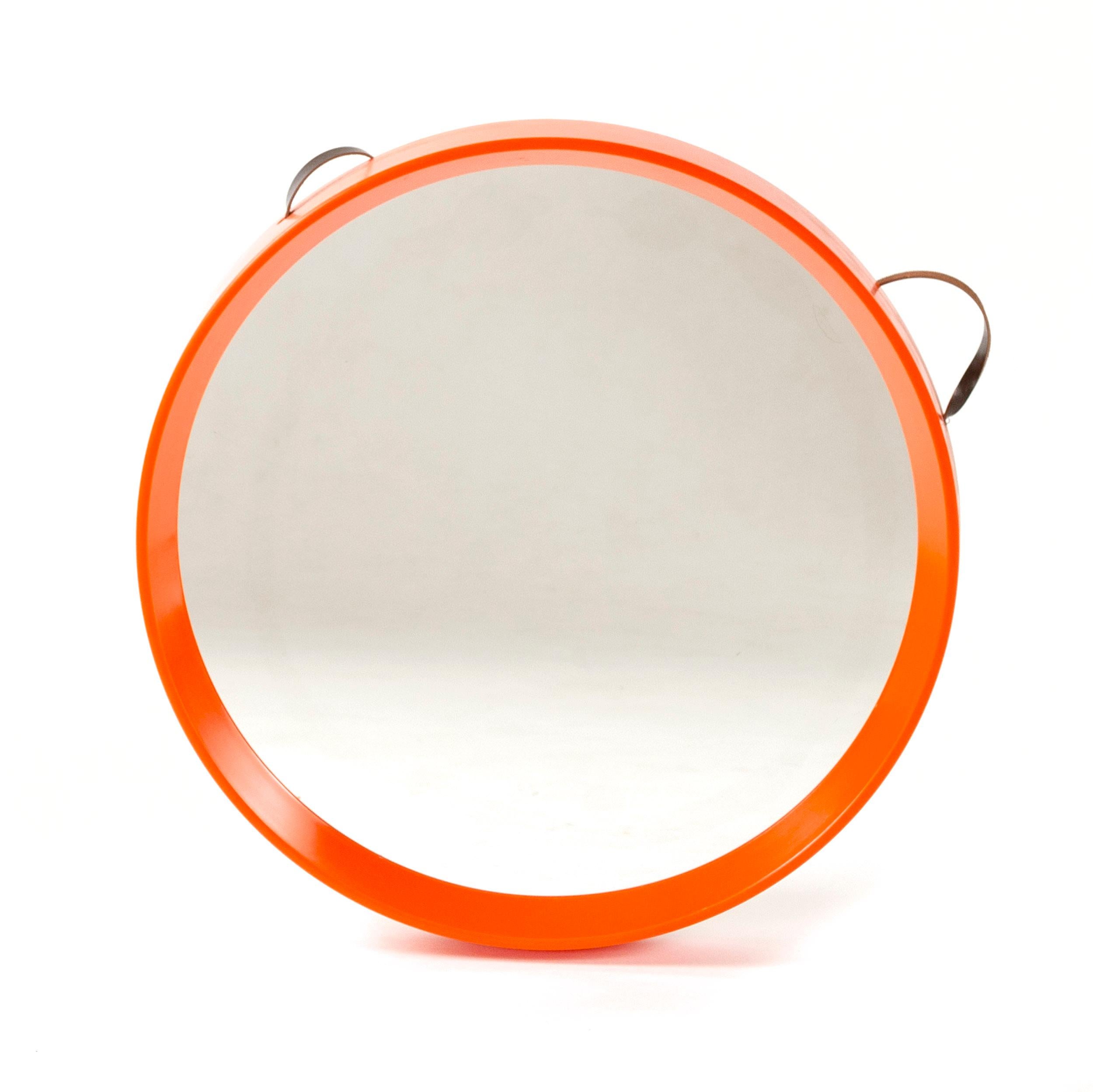 An orange, round tapered edge mirror which hangs from a thin leather strap.