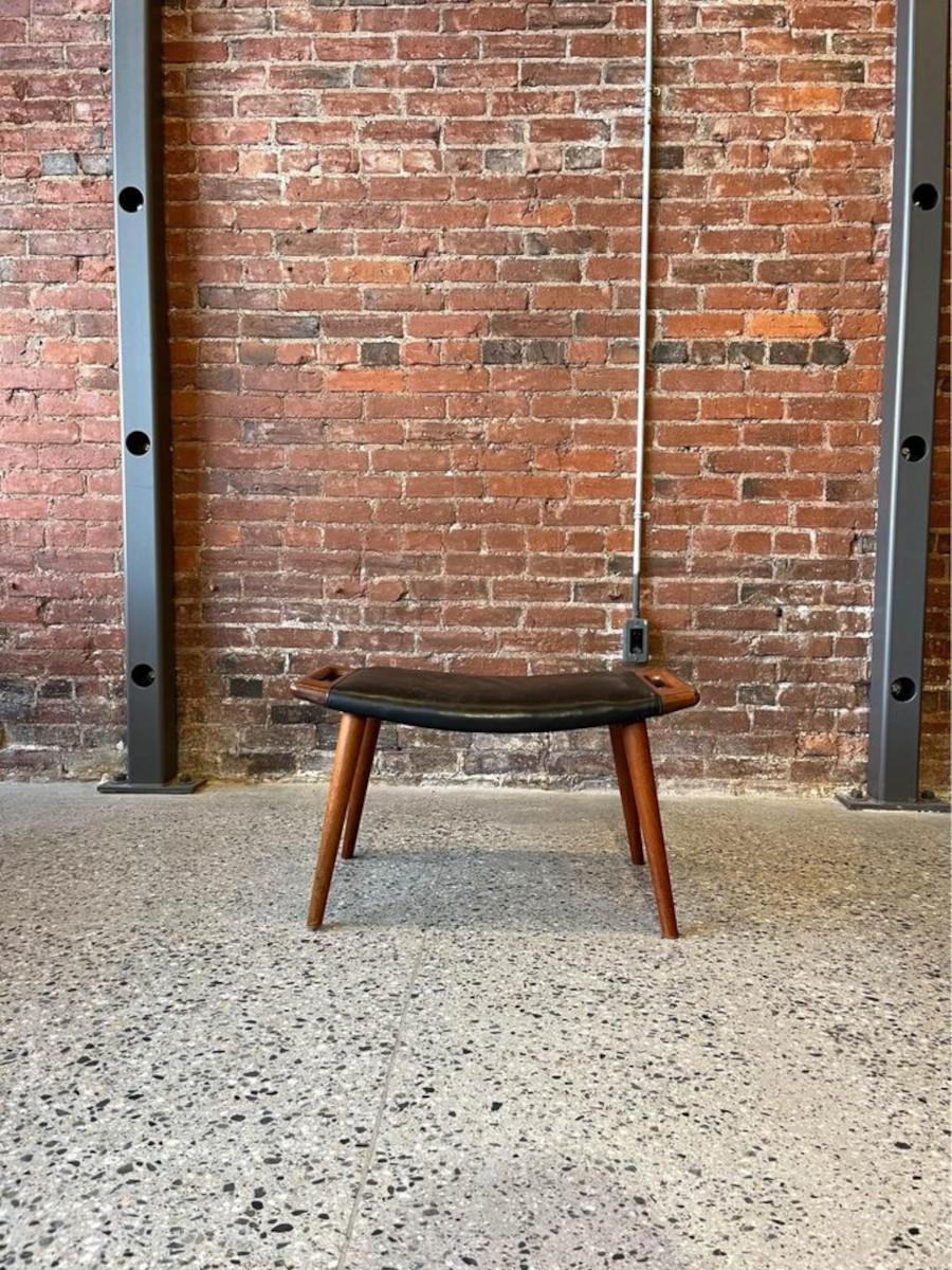 We are excited to offer a highly sought after stool for the iconic Papa Bear Chair designed by Hans Wegner in the 1950's. This authentic example features teak handles, teak legs, and the Danish control badge on the underside. Offered in as-found