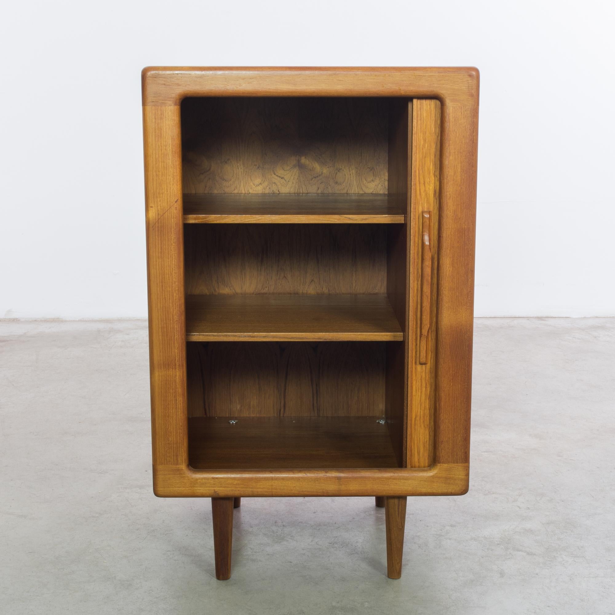 This 1970s Danish Teak Cabinet by Dyrlund epitomizes the era's penchant for minimalist design and superior craftsmanship. Constructed from the highest quality teak, its warm tones and smooth grain offer a welcoming presence in any room. The