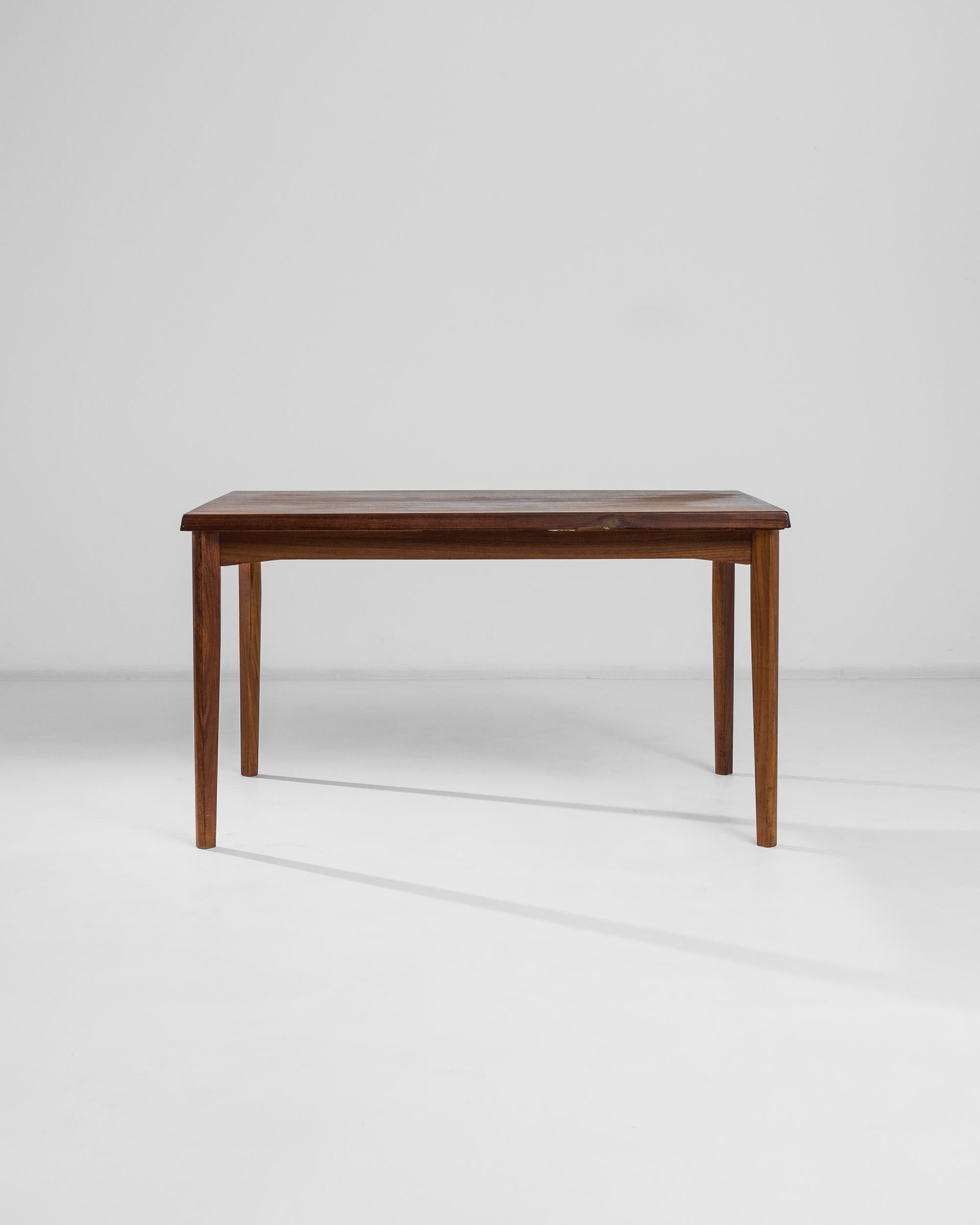 Following the core principles of Scandinavian design —simplicity, functionality and good taste —this Danish teak table manufactured circa 1970 features a practical folding tabletop that expands to twice its size. Visible asymmetry of the apron