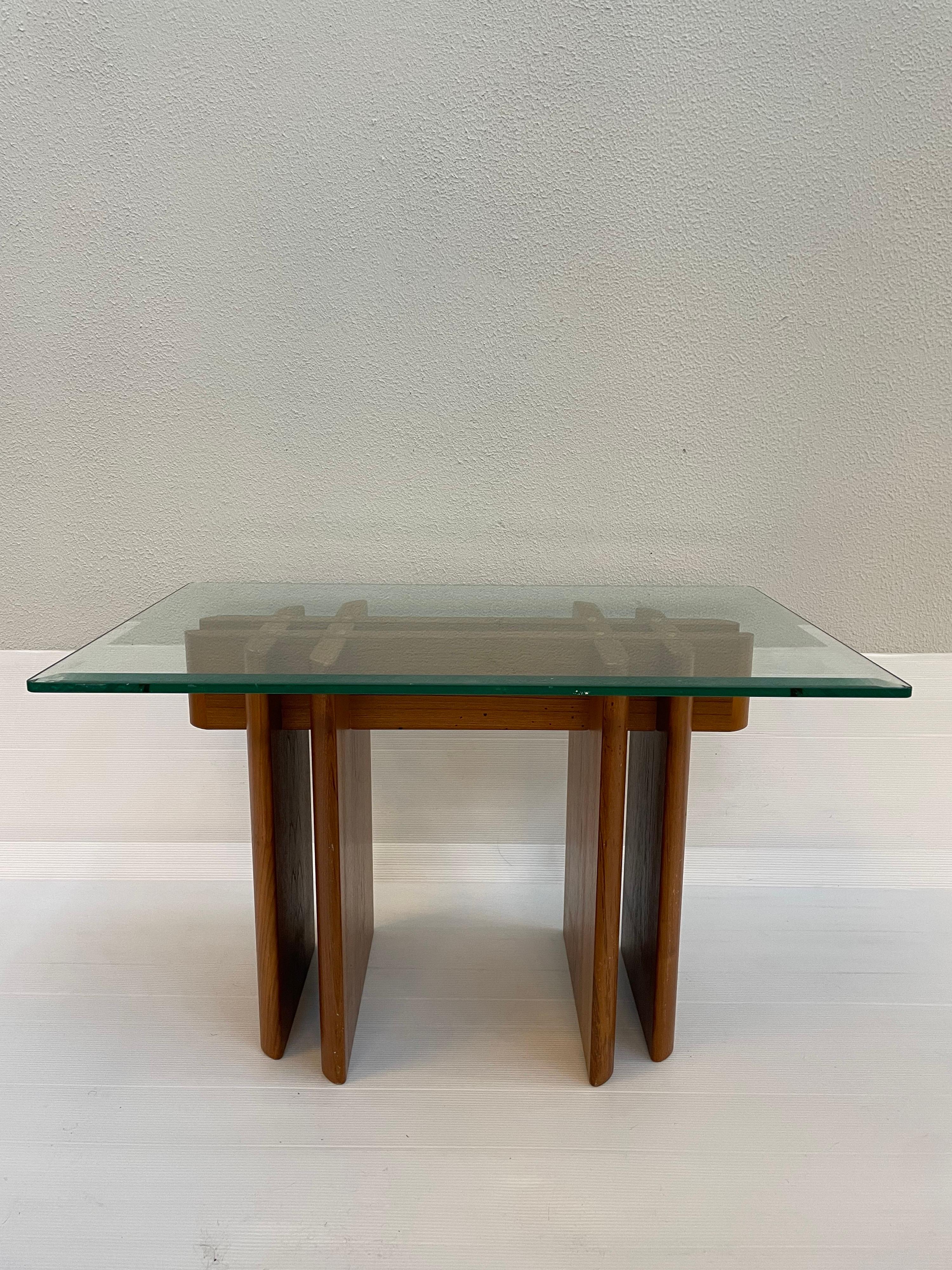 Vintage 1970s teak table by Gustav Gaarde for trekanten of Denmark. The glass top which has a 3/8 inch bevel, rests on an interlaced teak base. 1 out of 2 pieces of a set listed.