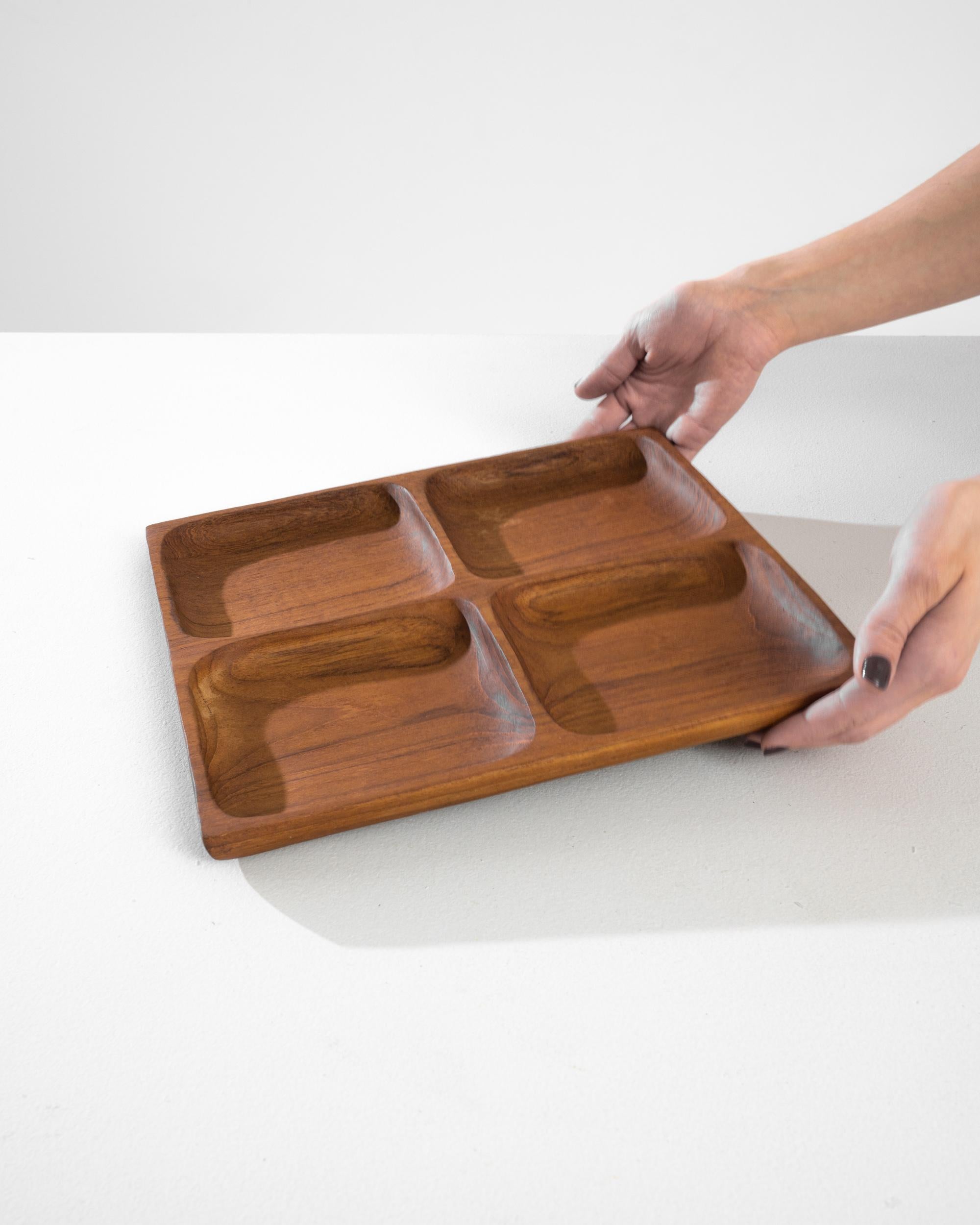 This 1970s Danish teak serving tray exemplifies the timeless elegance of Scandinavian design. Crafted from rich, warmly hued teak wood, it features a simple yet sophisticated four-compartment layout that marries form with function. The smooth,