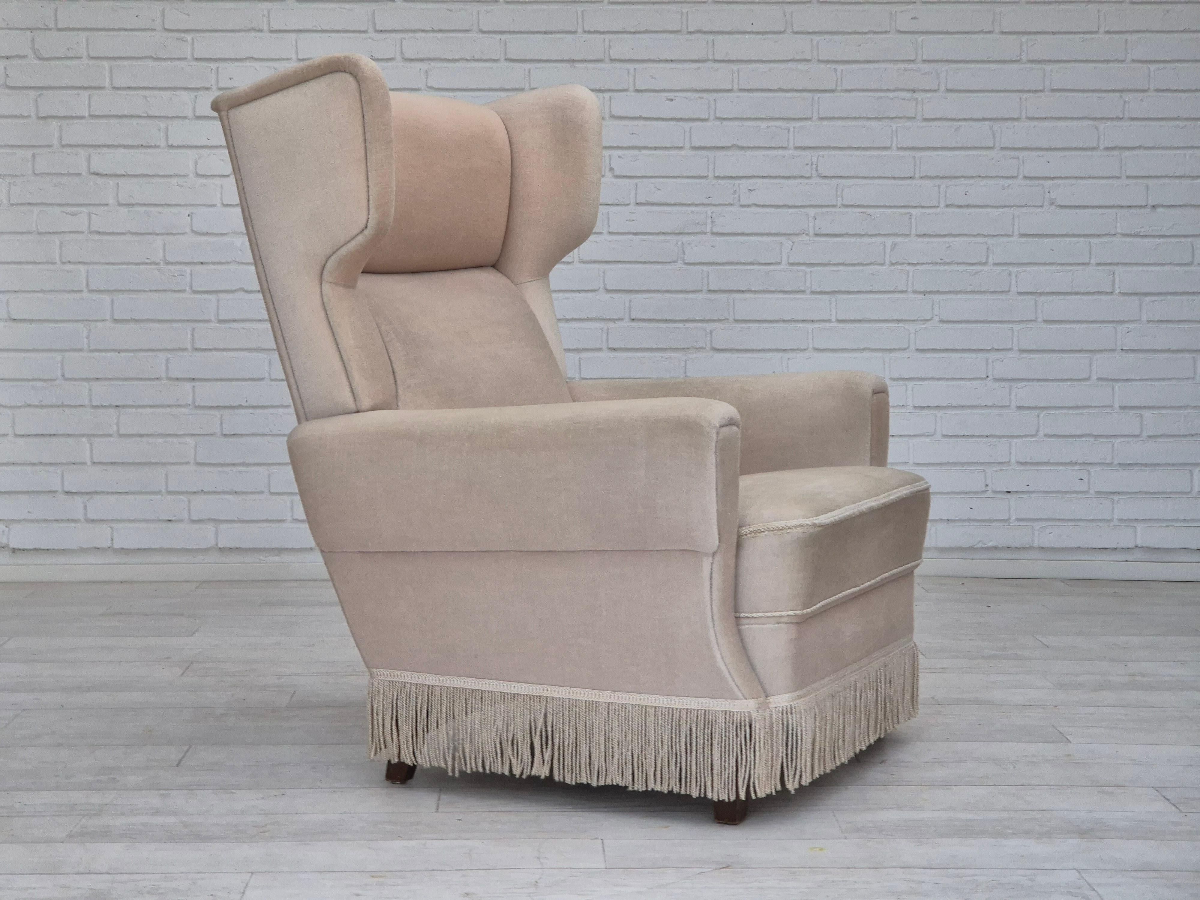 1970s, highback wingback chair in original good condition: no smells, no stains. White/light beige furniture velour, ash wood legs, springs in seat. Manufactured by Danish furniture maker in about 1970s. The chair was checked by craftsman.