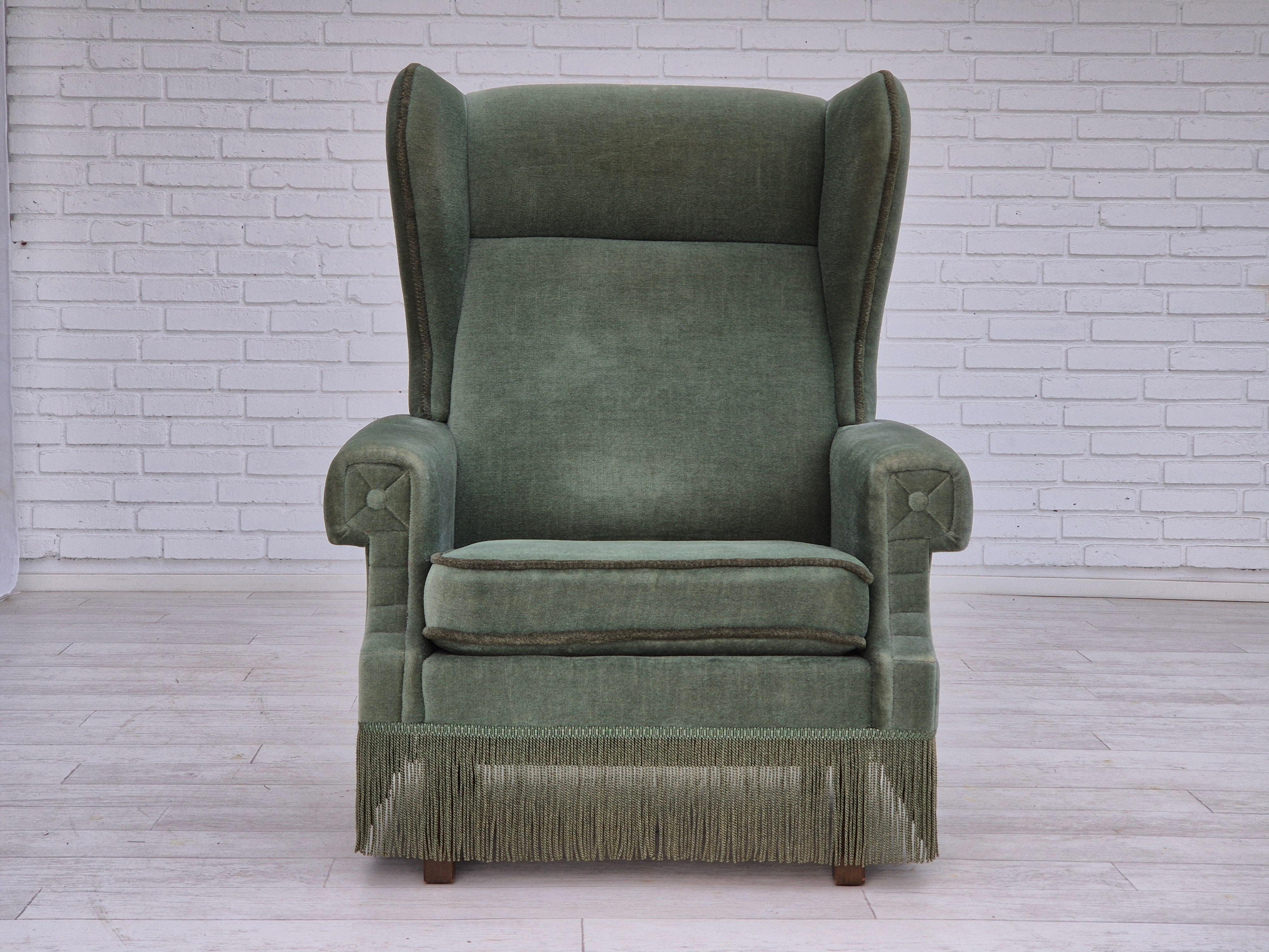 1970s, Danish wingback armchair in original very good condition: no smells and no stains. Original light green furniture velour, beech wood legs. Manufactured by Danish furniture manufacturer in about 1970-75s.