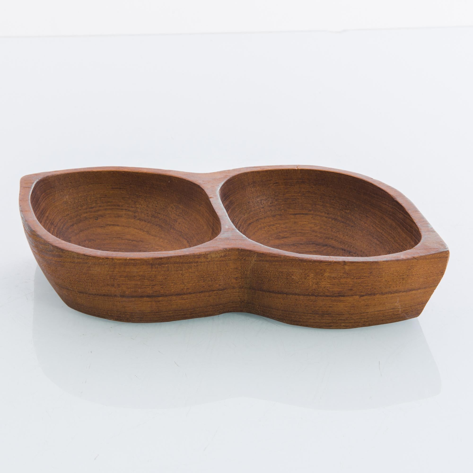 A wooden bowl from 1970s Denmark in the shape of a bean pod. Two partitions of the bowl, like two peas in a pod, mimic the natural form of the bean. The wood has a rich color with warm reddish tones and a dark grain, brought out by a fine polish.