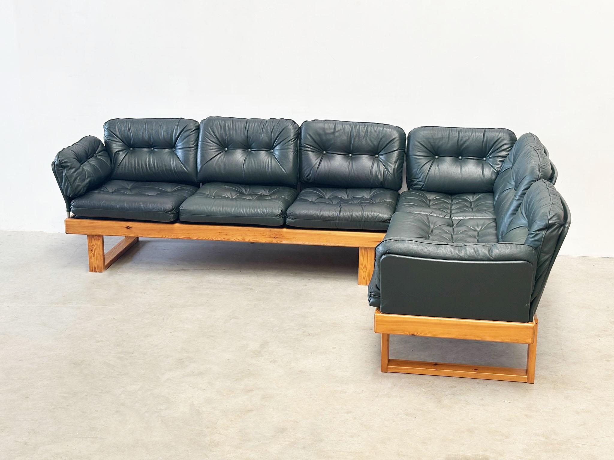 Questo divano modulare degli anni '70 è composto da due sezioni separate, che consentono una disposizione flessibile dei posti a sedere. Poggiati su una solida base in legno di pino, i cuscini in pelle verde scuro possono essere riposizionati o