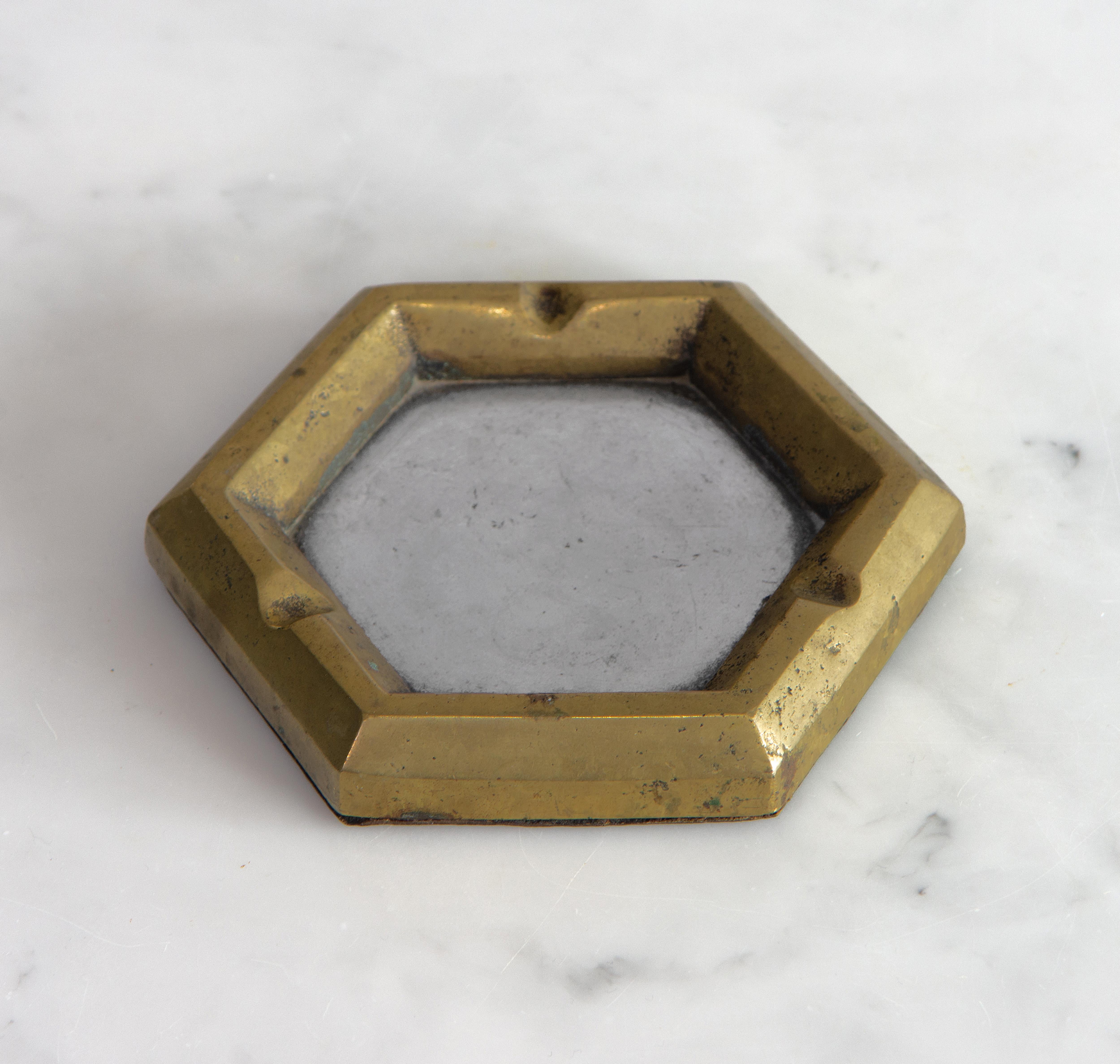 An aluminium and cast brass ashtray designed by David Marshall, circa 1970-80s.

Delivery included to mainland UK.

Demonstrating the sculptor's signature use of contrasting metals. The underside has a leather base with the imprinted maker's mark.
