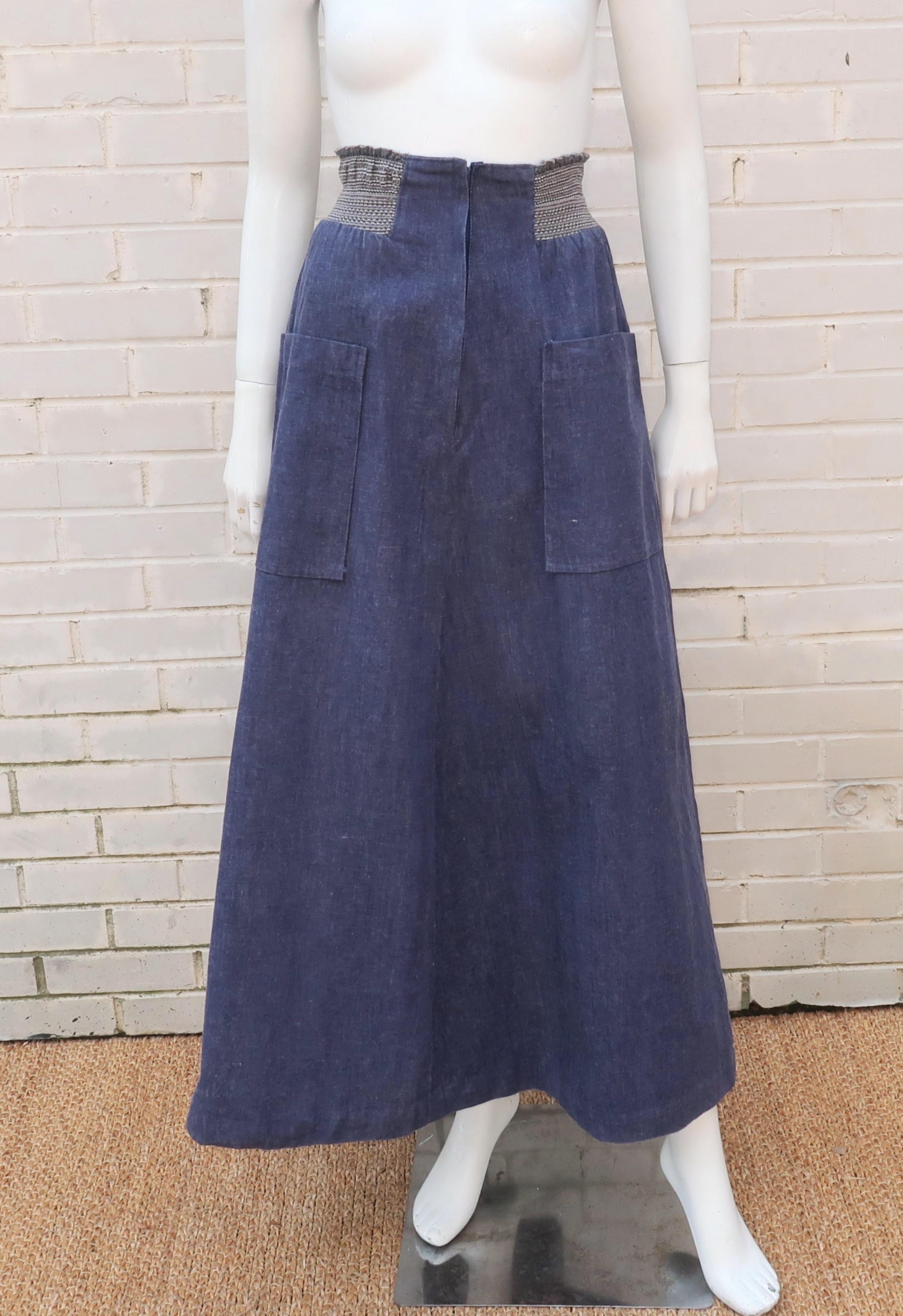 A boho chic 1970’s denim maxi skirt by English designer, David Silverman.  The skirt features an elasticized ribbed high waistband and extra large front pockets.  It zips and hooks at the front with an a-line silhouette that would be period perfect