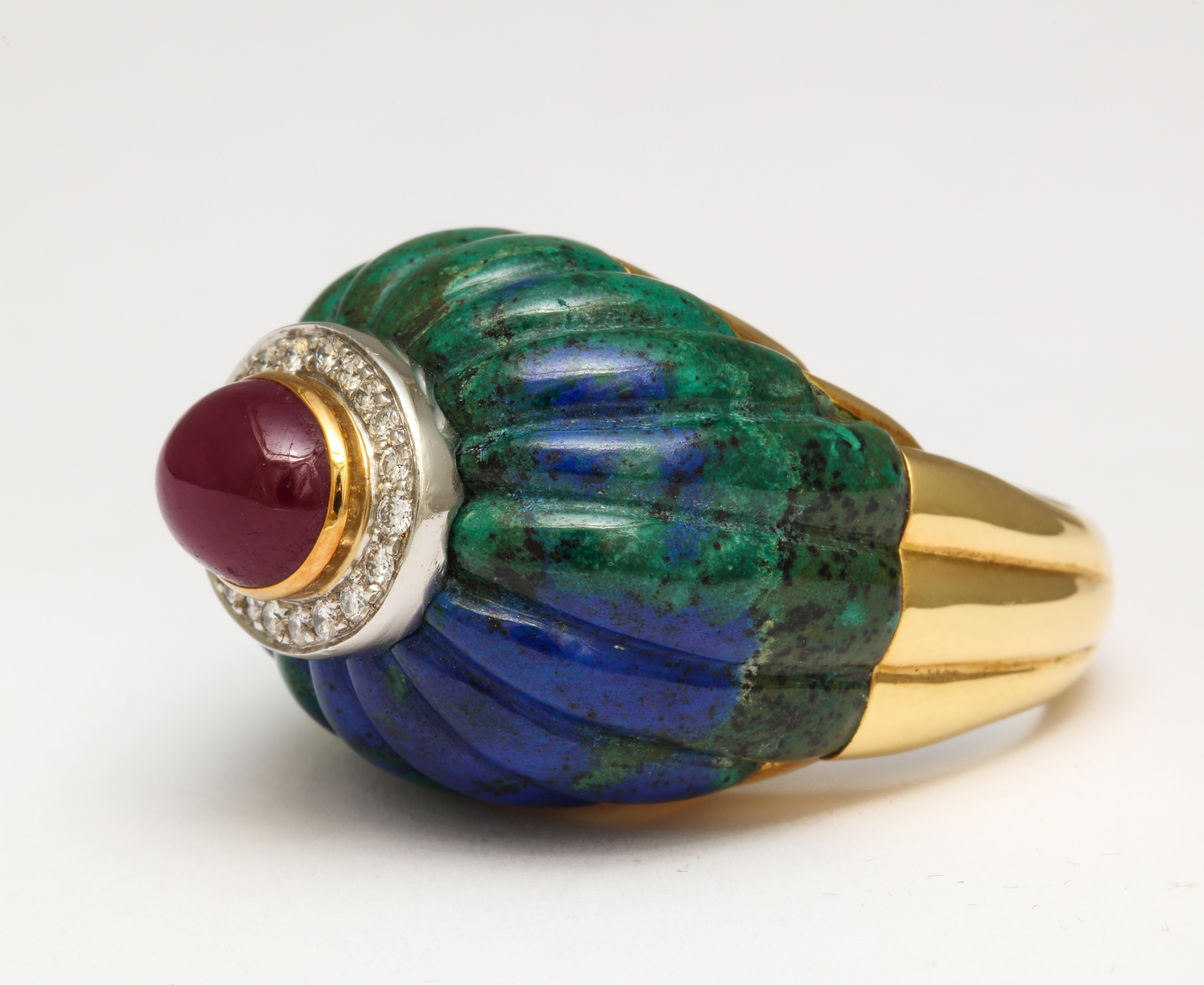 From renown New York jewelry designer David Webb we offer a 1970s 18K gold ring of hand carved azurite-malachite set with a large cabochon ruby over an oval bed of platinum set diamonds. Measured as looking from above: 5/8 inch x 1 1/8 inches, and