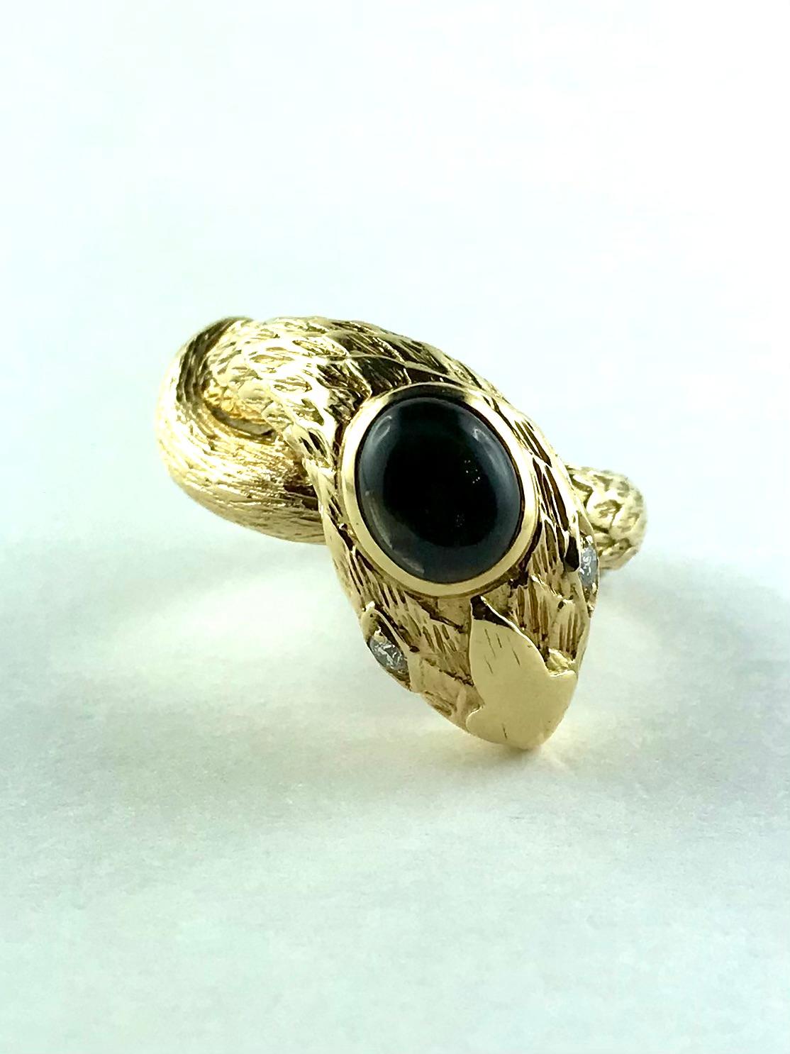 Sleek 1970’s David Webb bypass Ring  designed as a coiling snake with a detailed scale pattern. Mounted in 18 k Yellow Gold and adorned on the head with a star Sapphire oval cabochon,  the eyes are highlighted by two brilliant-cut Diamonds. 
A