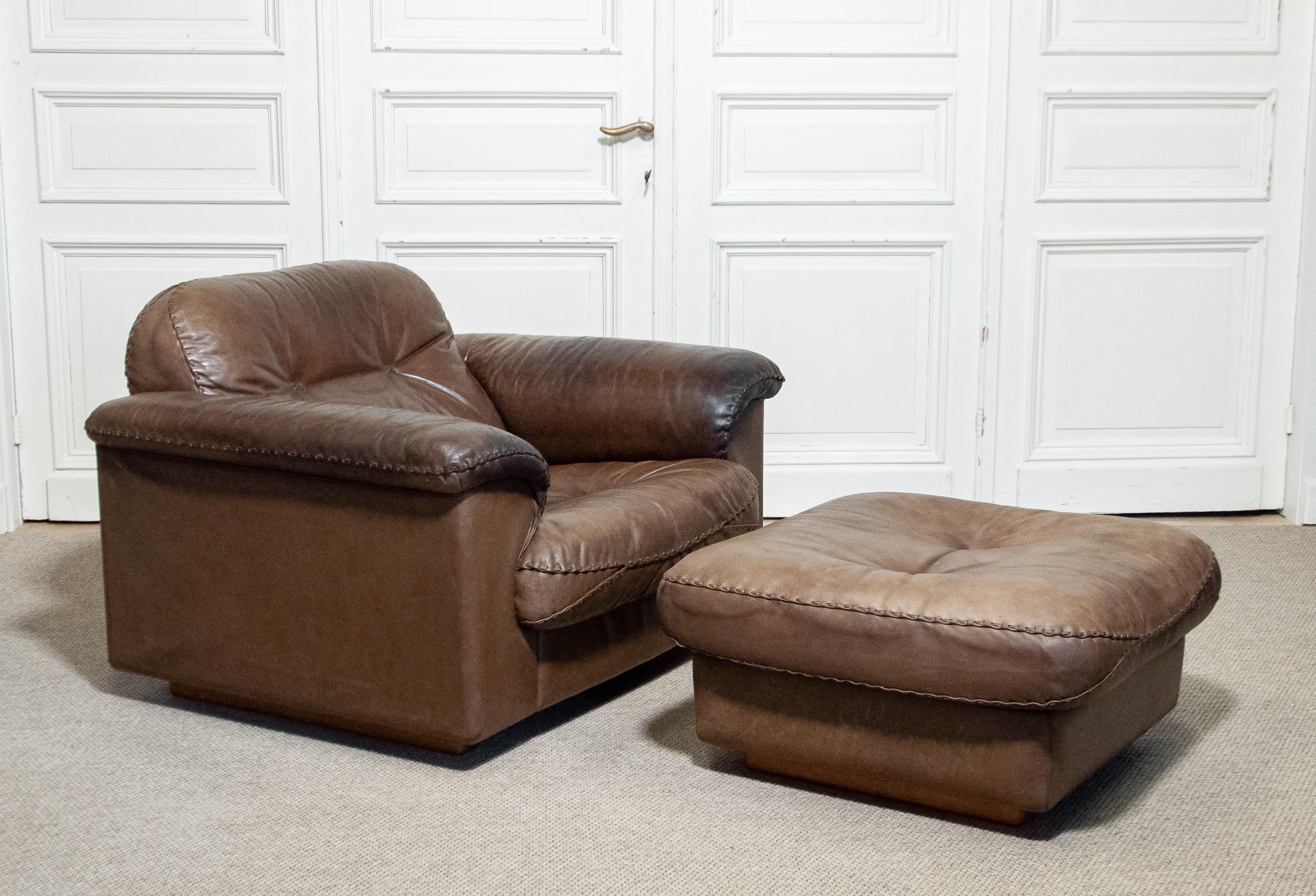 De Sede DS-101 reclining lounge chair with matching ottoman, Switzerland, 1970s. Upholstered in rich brown leather with hand-stitched detailing, this iconic relax chair feature adjustable seat mechanisms for maximum comfort. The square ottoman