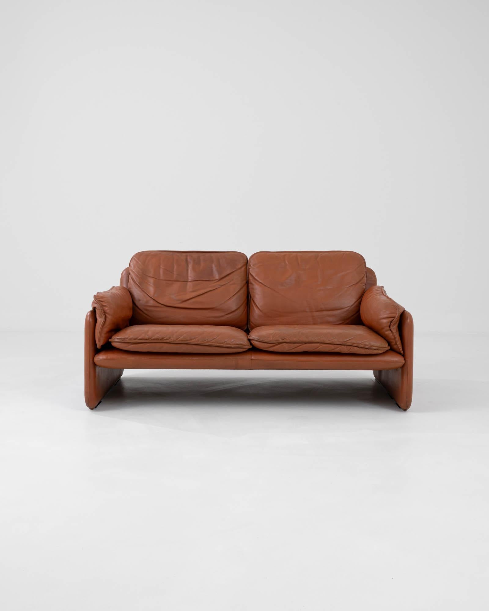 Hand-made in Switzerland by renowned furniture manufacturers De Sede, this 1970s leather sofa is simultaneously sophisticated and playful. The soft, slouchy folds of the cushions and armrests give a relaxed inflection to the structural silhouette,
