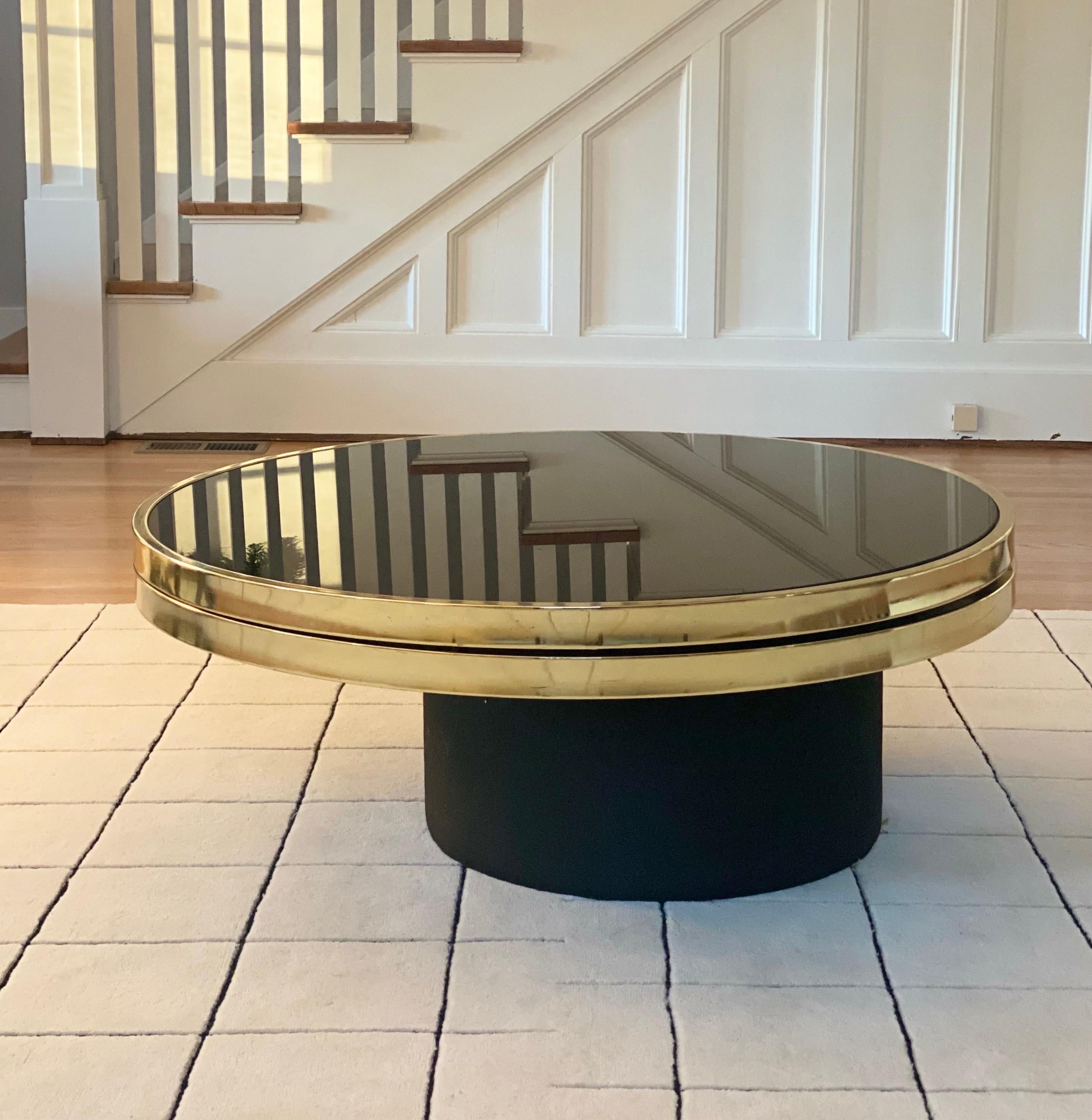 We are very pleased to offer a minimalist and modern coffee table by Richard D. Berry Jr for Design Institute of America, circa the 1970s. Featuring two luxurious, glass plate insets with polished brass edging and a black fabric covered drum base,
