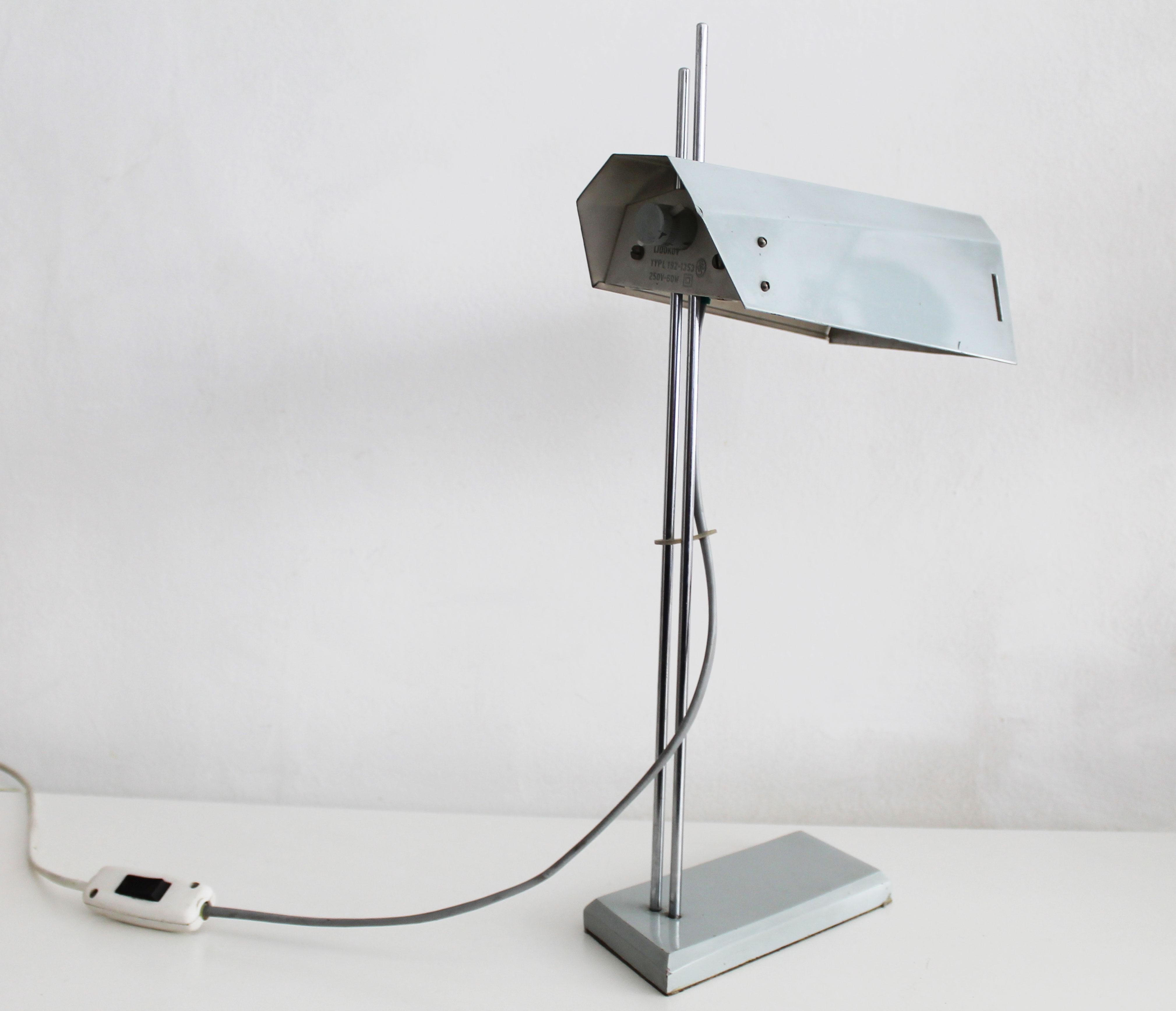 This desk lamp was designed in the late 1970's, and was produced by Lidokov in former Czechoslovakia.

The lampshade is held by two steel rods. This allows the user to adjust the lampshade to different positions. The rods are screwed into round