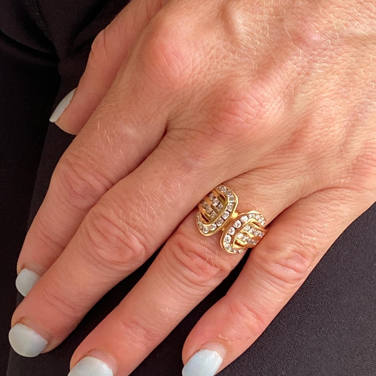 1970's diamond buckle ring fashioned in 14 karat yellow gold. The ring features 40 channel set round brilliant cut diamonds weighing approximately 1.00 carat total weight and graded H-I color and SI clarity. The ring is currently size 5.5 (can be