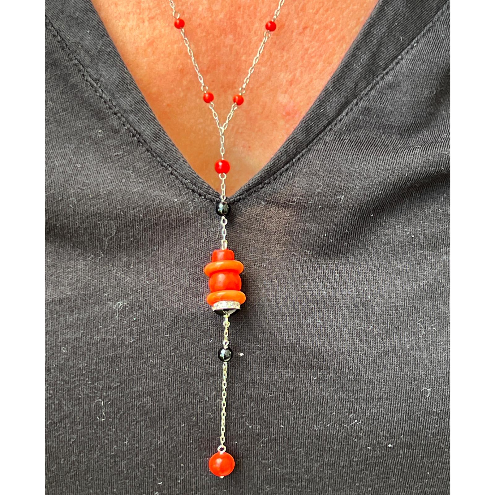 1970's coral, onyx, and diamond Y drop necklace handcrafted in platinum. The necklace features coral and onyx beads set with 12 diamonds weighing approximately .25 CTW graded H/VS. The platinum link necklace measures 20.5 inches in length and the