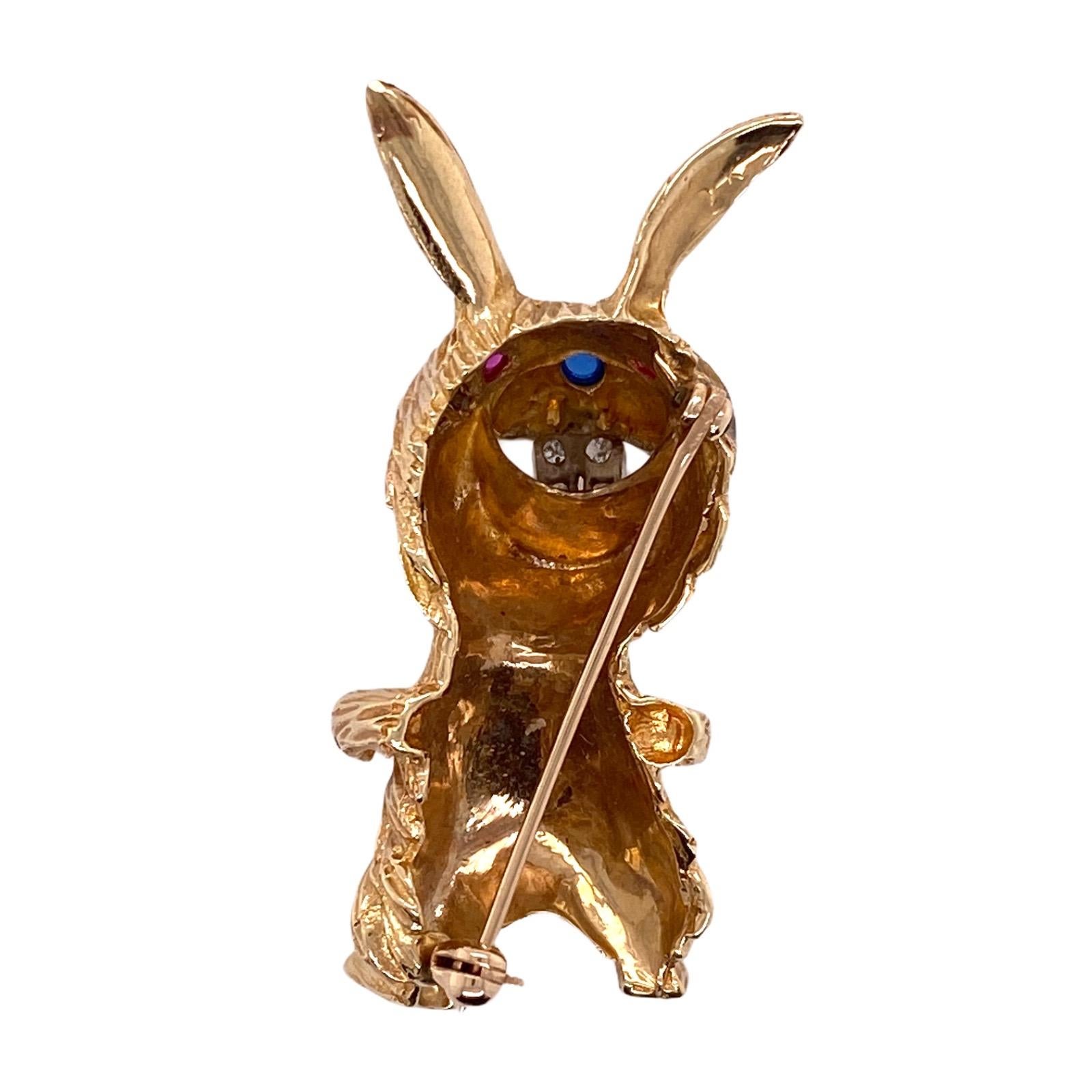 Adorable rabbit pin fashioned in 14 karat yellow gold. The 1970's brooch features 12 diamonds weighing approximately .24 carat total weight, two ruby eyes, and a sapphire nose. The pin measures 1.0 x 1.75 inches. 