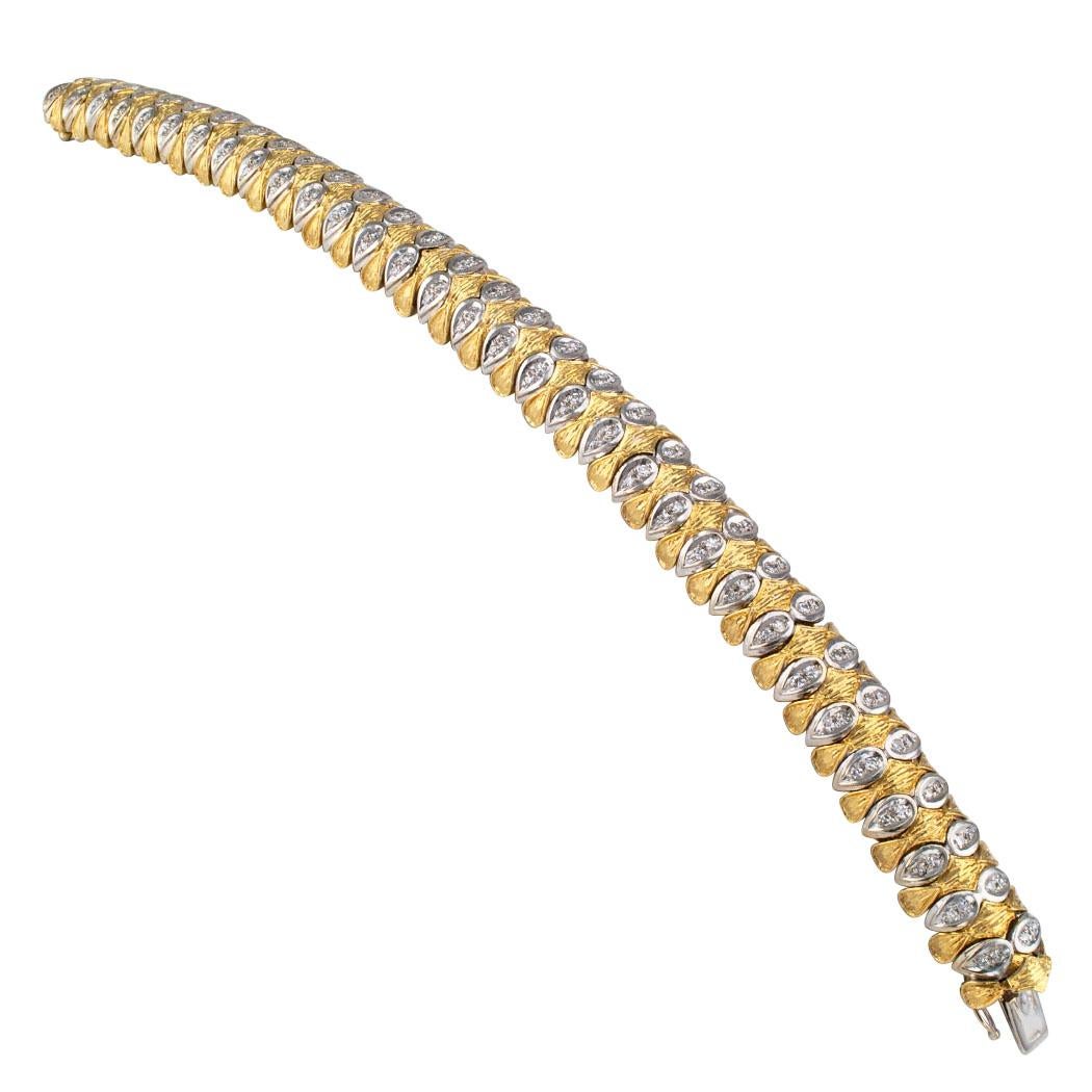 1970s two tone gold and diamond bracelet. The flexible 18-karat gold design features a course of textured yellow gold links tightly linked with alternating white gold links set with diamonds, the one hundred twenty-eight diamonds totaling