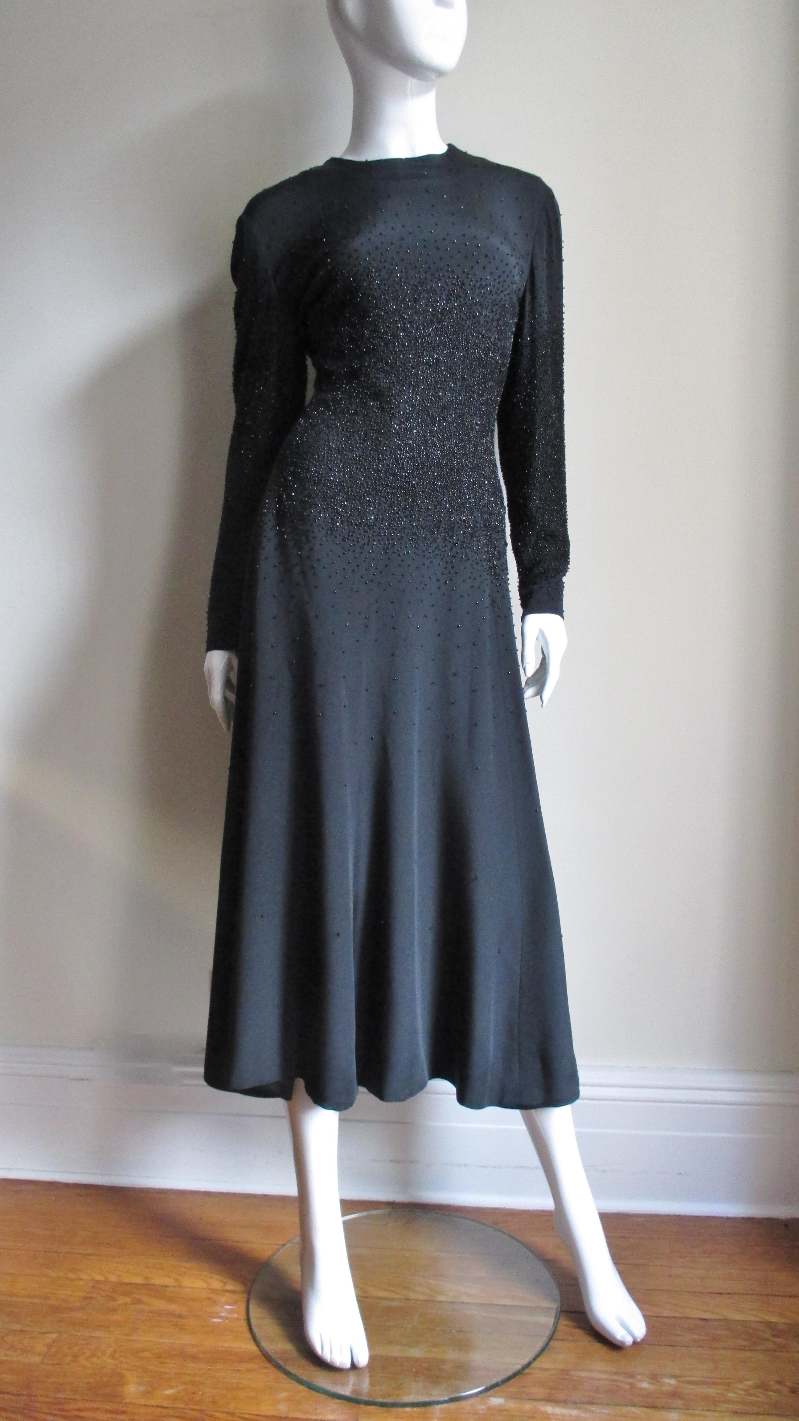 A fabulous black midi length silk dress from Donald Brooks.  It has a crew neckline, long sleeves with zippers at the wrists and is semi fitted through the bodice then flares into a full skirt.  What sets it apart aside from it's elegant simplicity