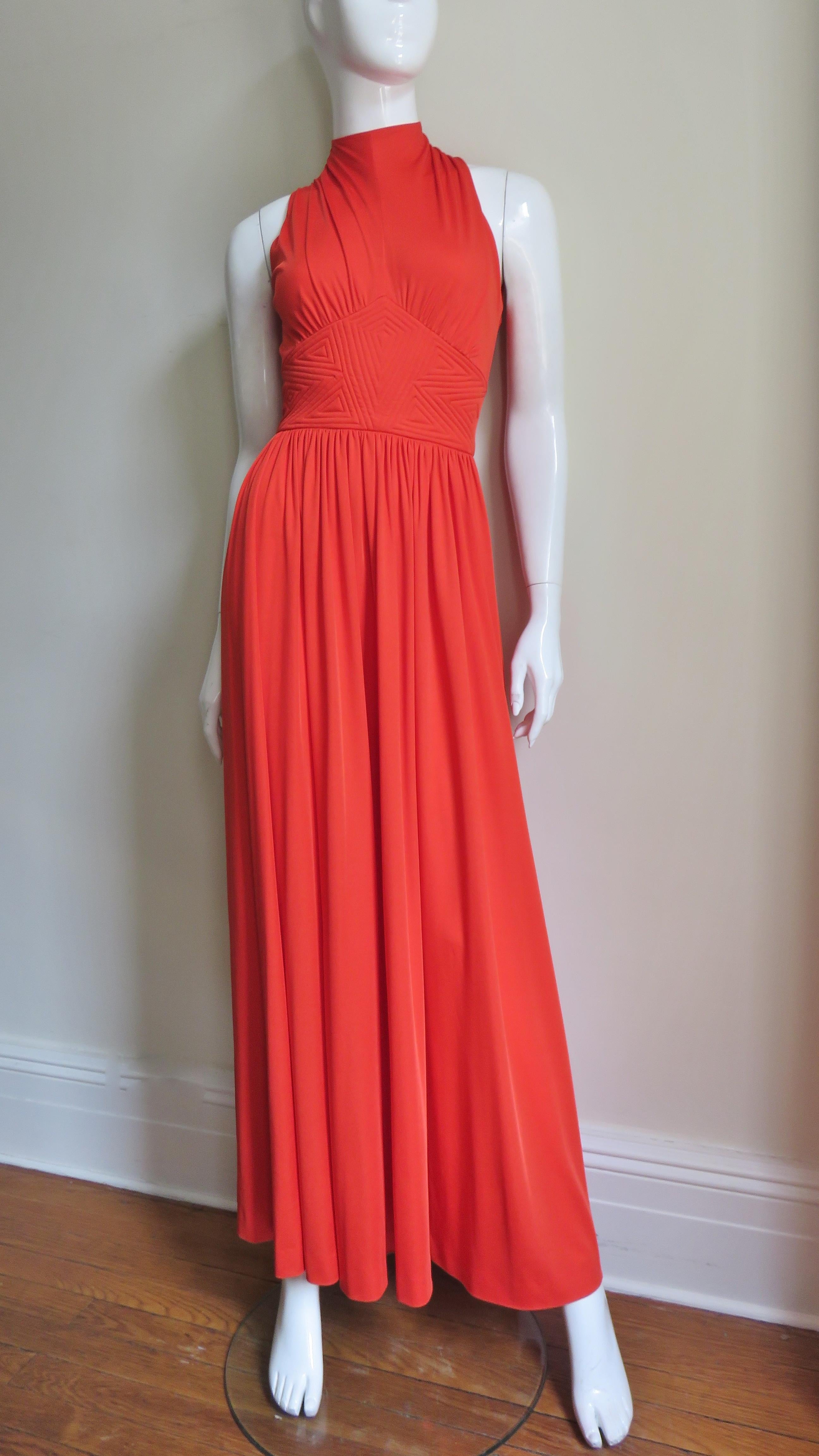 A beautiful orange jersey maxi dress designed by Donald Brooks with an elaborate band of trapunto embroidery at the waist.  The dress is sleeveless with cut in shoulders, a high neckline and an inset at the waist coming to a point just below the