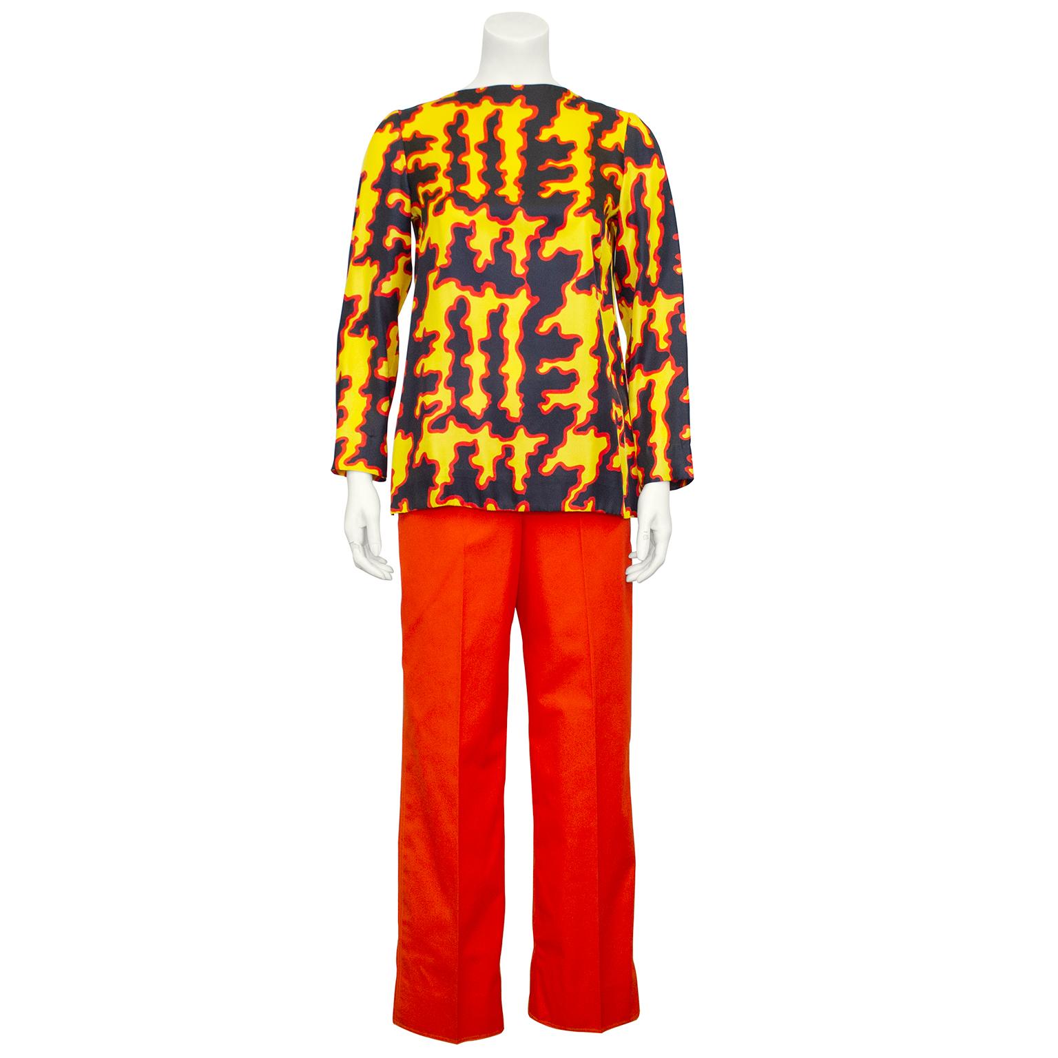 Fabulous Donald Brooks three piece ensemble from the early 1970s. Features matching fiery orange cotton jacket and trousers with silk top. Jacket has a rounded notched collar, gold metal buttons and rounded diagonal patch pockets at bust. Shirt is