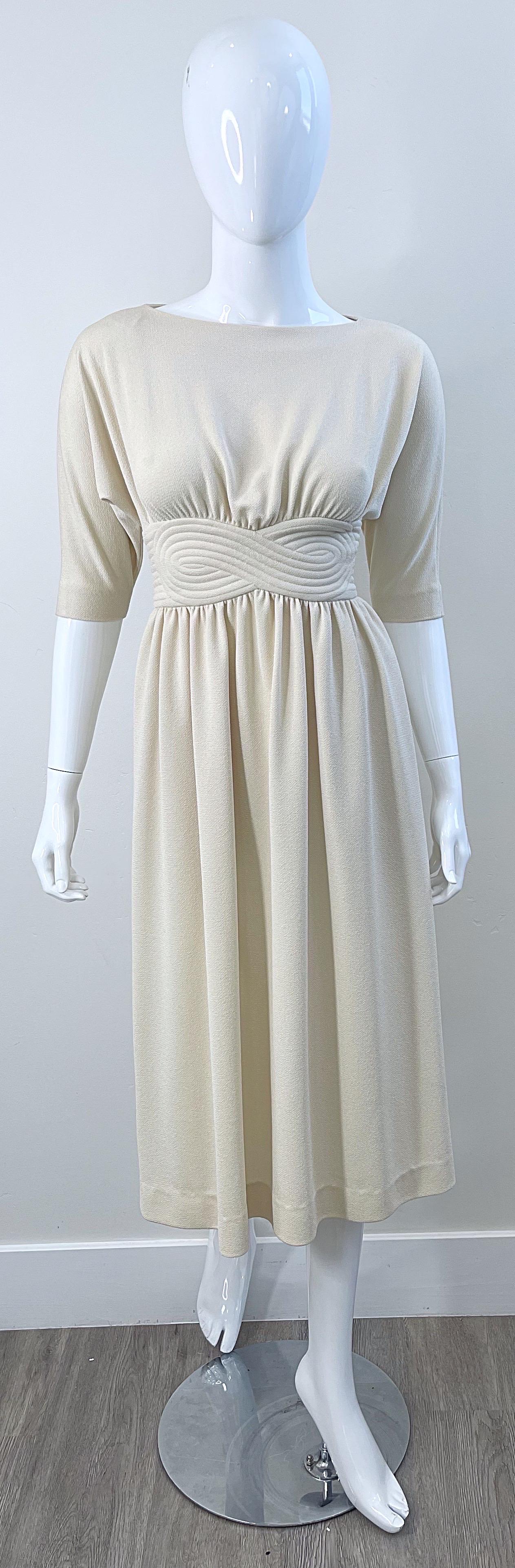 Chic early 70s DONALD BROOKS ivory off-white 3/4 sleeves crepe dress ! Features a tailored bodice, with a Grecian inspired waistband. Hidden zipper up the back with fabric covered buttons on top. Pockets at each side of the hips. 
Brooks was an