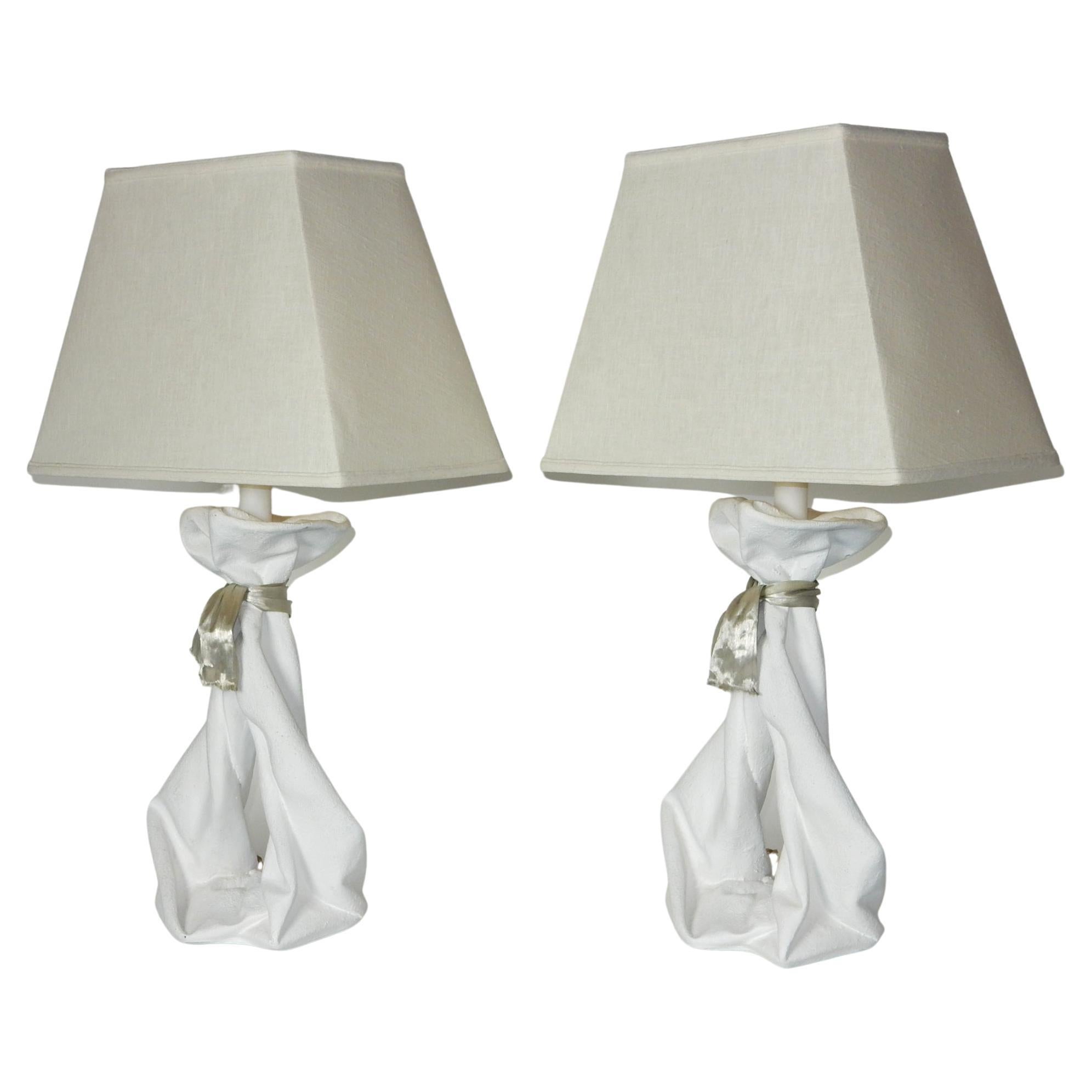 A realistic pair of draped plaster table lamps from the late 1970's or early 80's..
Chalky white plaster molded into flowing drapery
tied off with a metallic ribbon. 
Large size measuring 24in to socket.
These show well with no chips, cracks nor