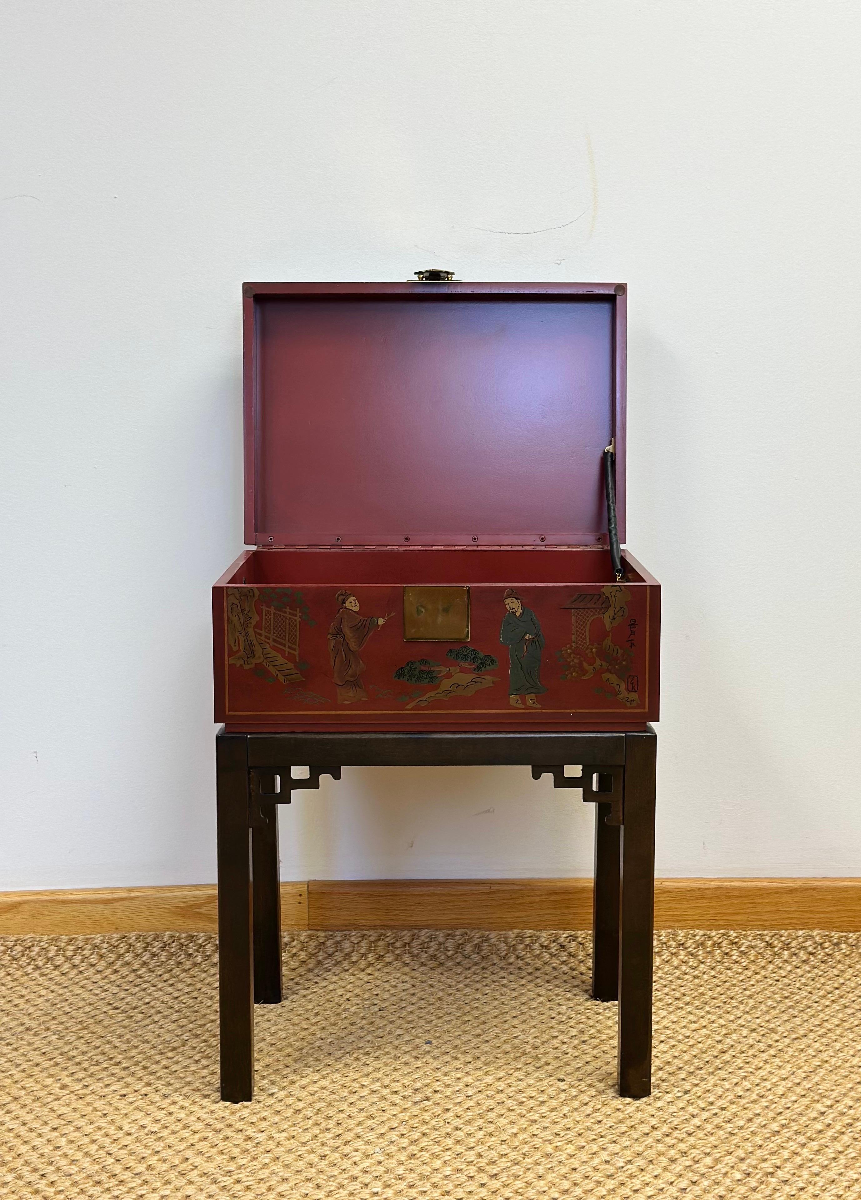 Siamo lieti di offrire una scatola da appoggio asiatica vintage di Drexel Heritage, risalente agli anni '70 circa. Dipinto a mano con figure e paesaggi tradizionali cinesi, presenta una ricca lacca rossa e dettagli dorati che emanano un fascino