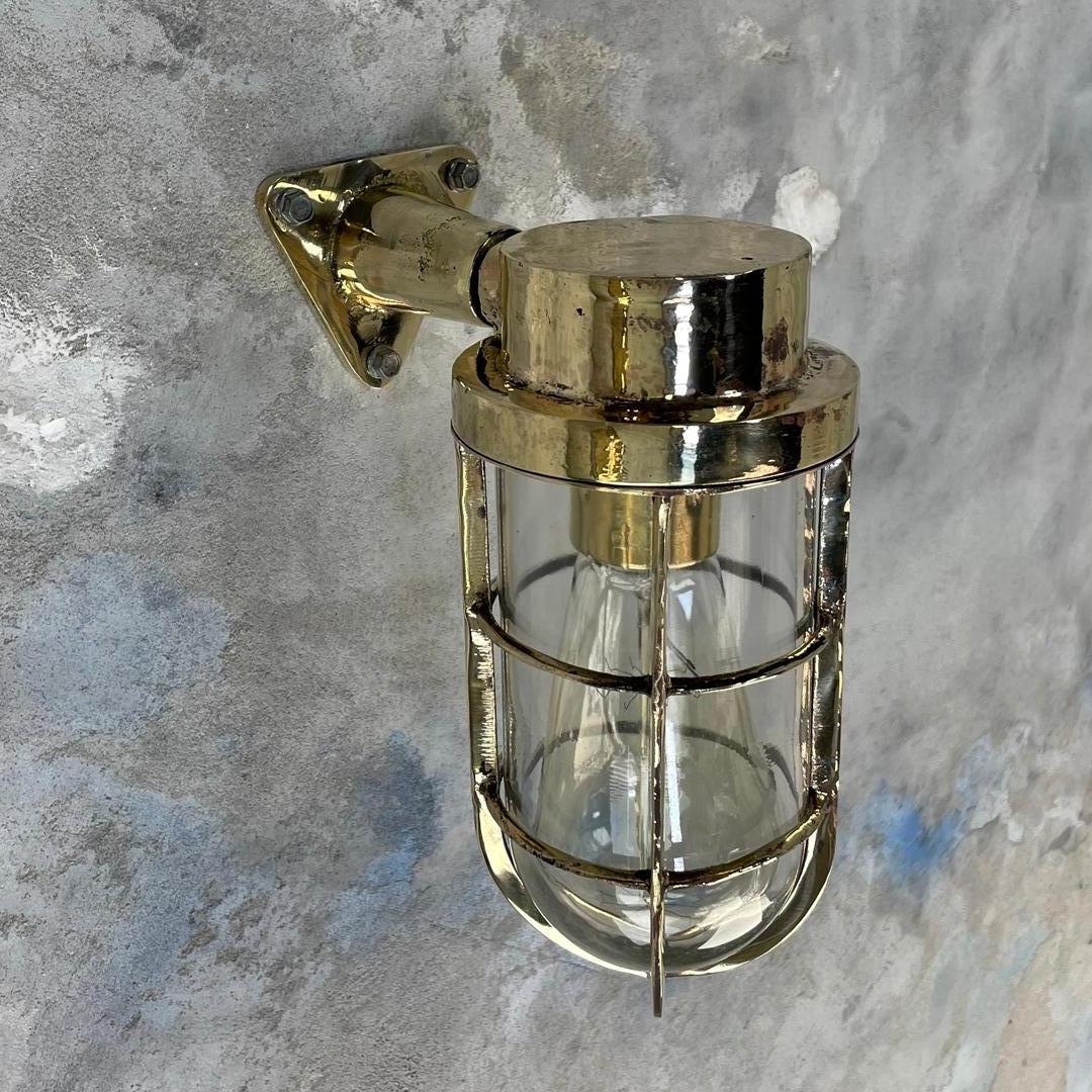 Cast brass 90 degree wall sconce by Industrial Rotterdam of Holland.

These lamps made circa 1970's are robust nautical fittings with tempered glass signed 'IR' and protective cage, the cage screws down over the glass shade and they are mounted