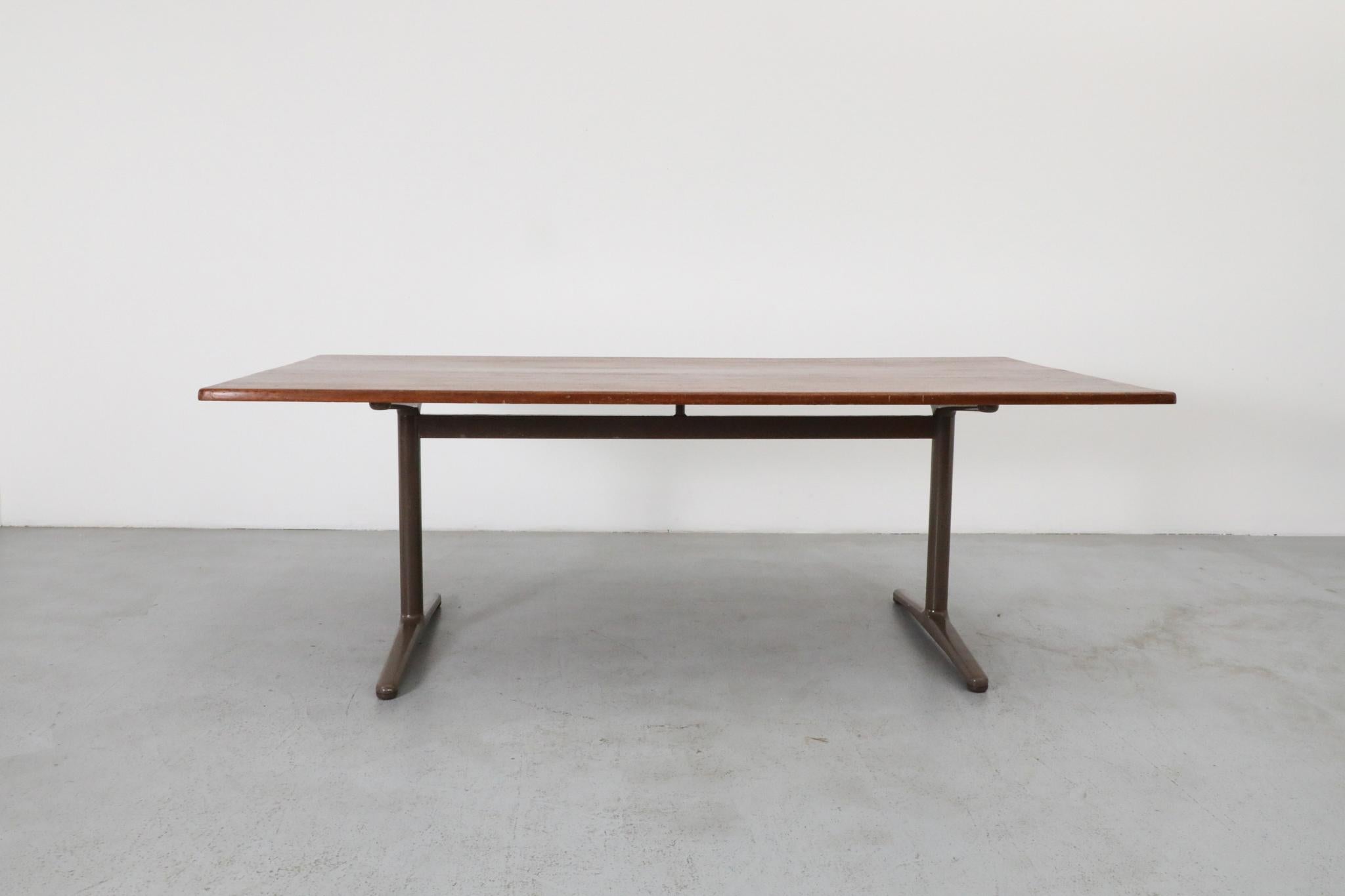 Mélange convaincant de design industriel néerlandais et de caractère usé par le temps, cette table de travail ou de conférence des années 1970 associe une base en métal émaillé marron de Gispen à un plateau en teck massif richement patiné. Gispen,