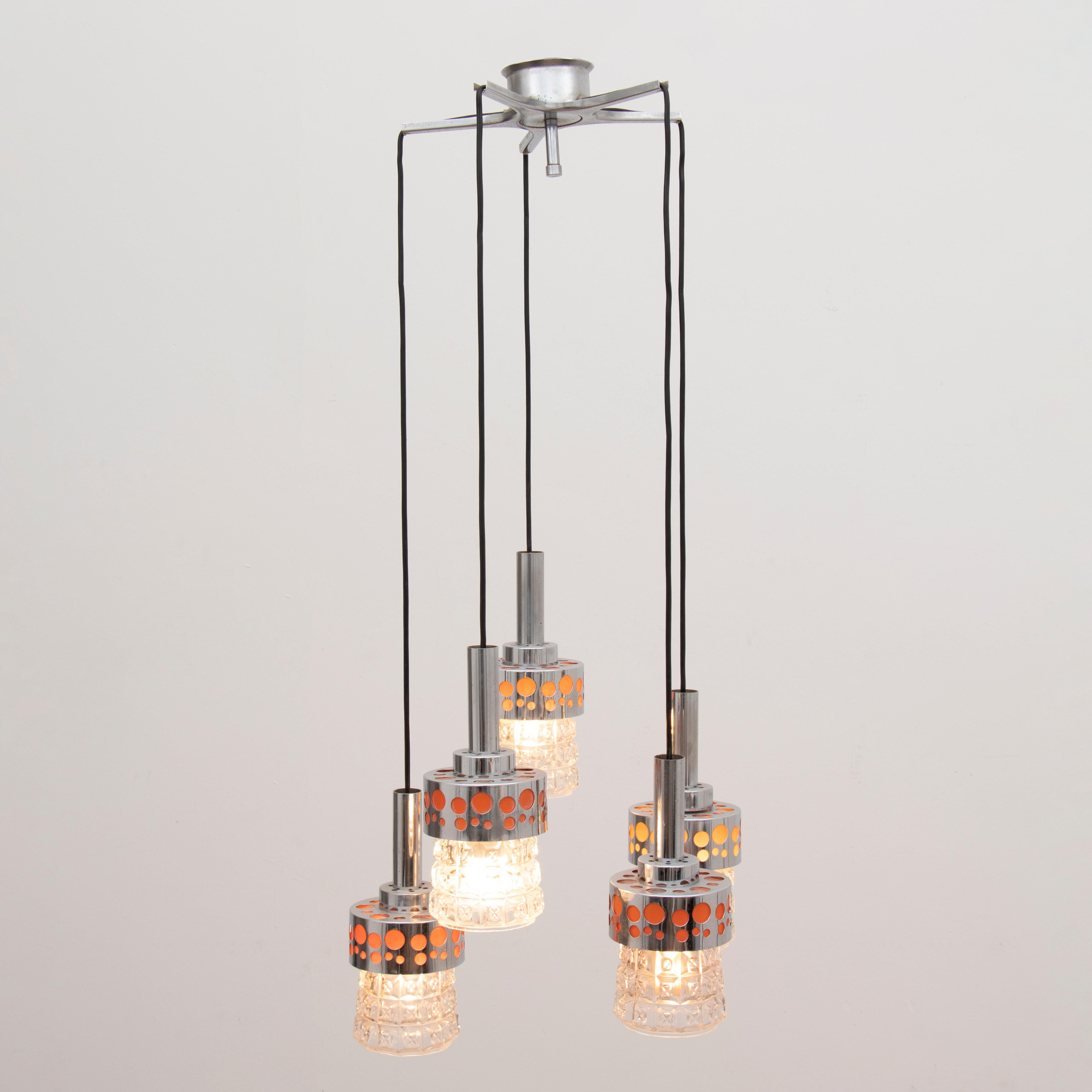 A 1970s orange, glass and chrome five shade pendant light manufactured in the Netherlands by RAAK Amsterdam. PAT tested to UK and European standards and in full working order. The five shades hang from a metal star formed ceiling plate with each