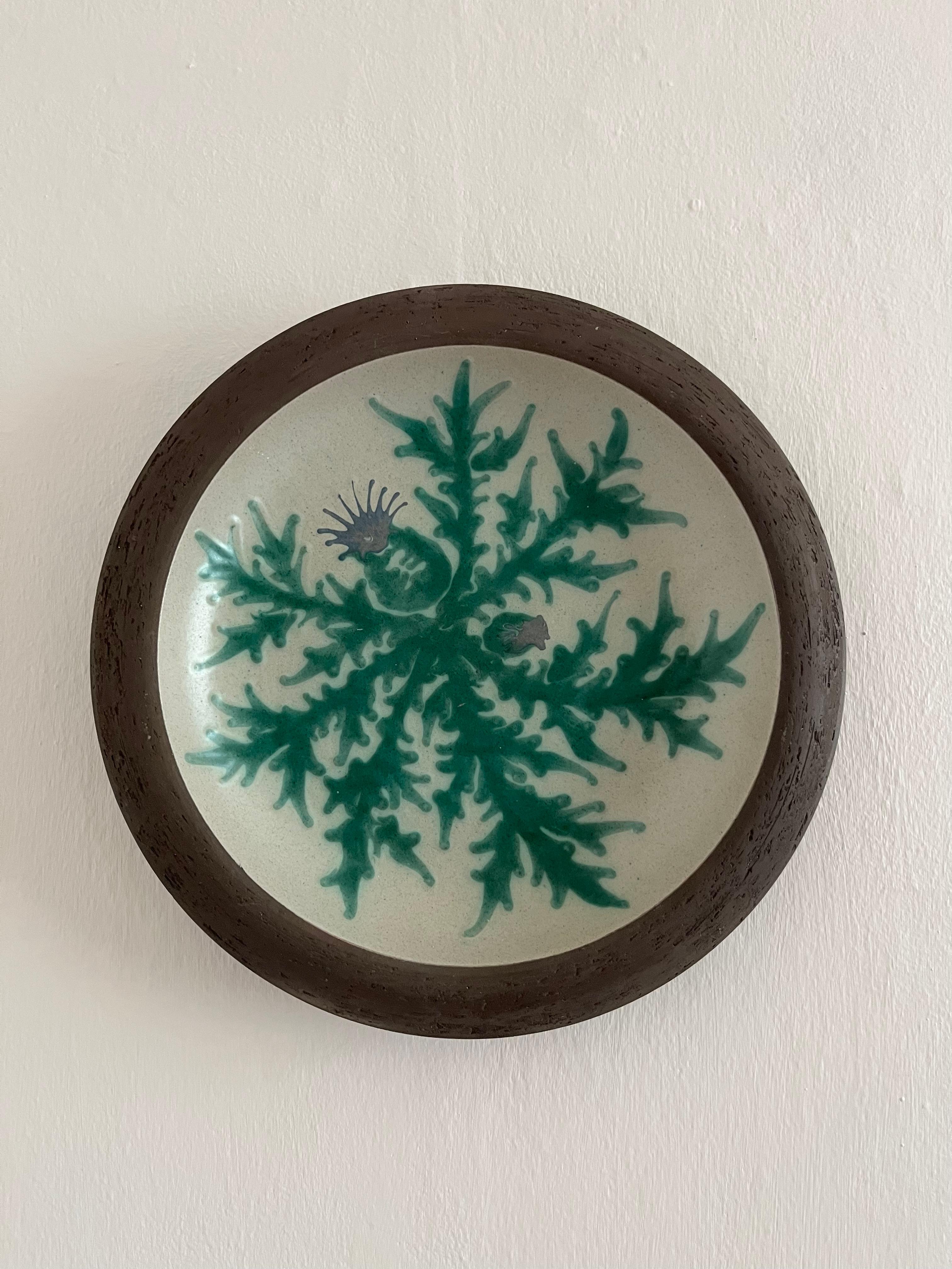 1970s earthenware wall decoration with thistle decorations. Earthenware wall decoration / dish with glazed front with thistle decorations and a matte backside signed by the ceramicist from Danish Pottemagerværkstedet Sjællands Odde.

Diameter: 29,5