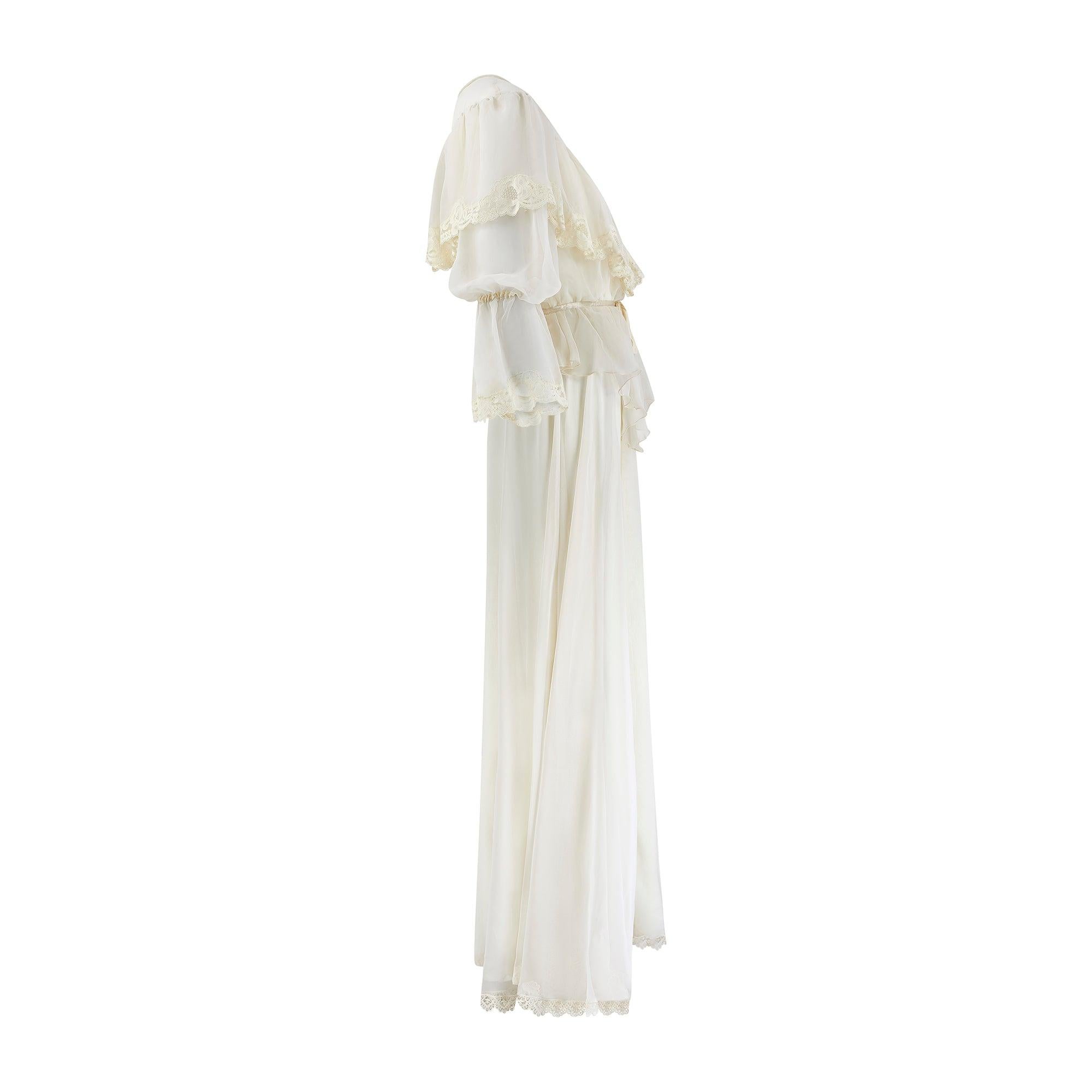 This enchanting 1970s wedding gown draws on the decade’s love affair with certain aspects of 'Victorina' and Edwardian tailoring. It is crafted from a manmade, off-white chiffon trimmed with lace and ribbon in a blouson style that epitomised the
